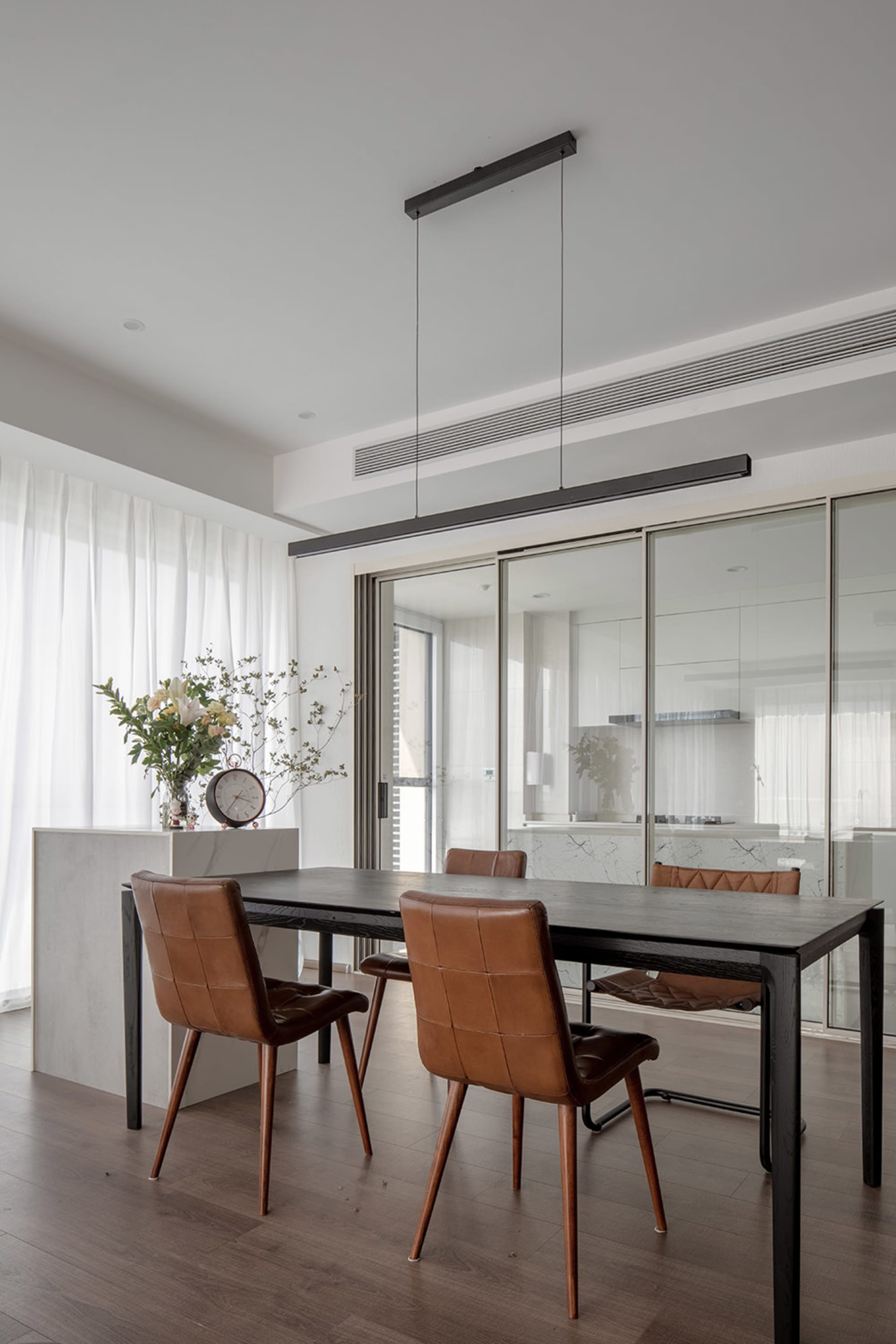 Modern minimalist dining room featuring wood table and leather chairs.