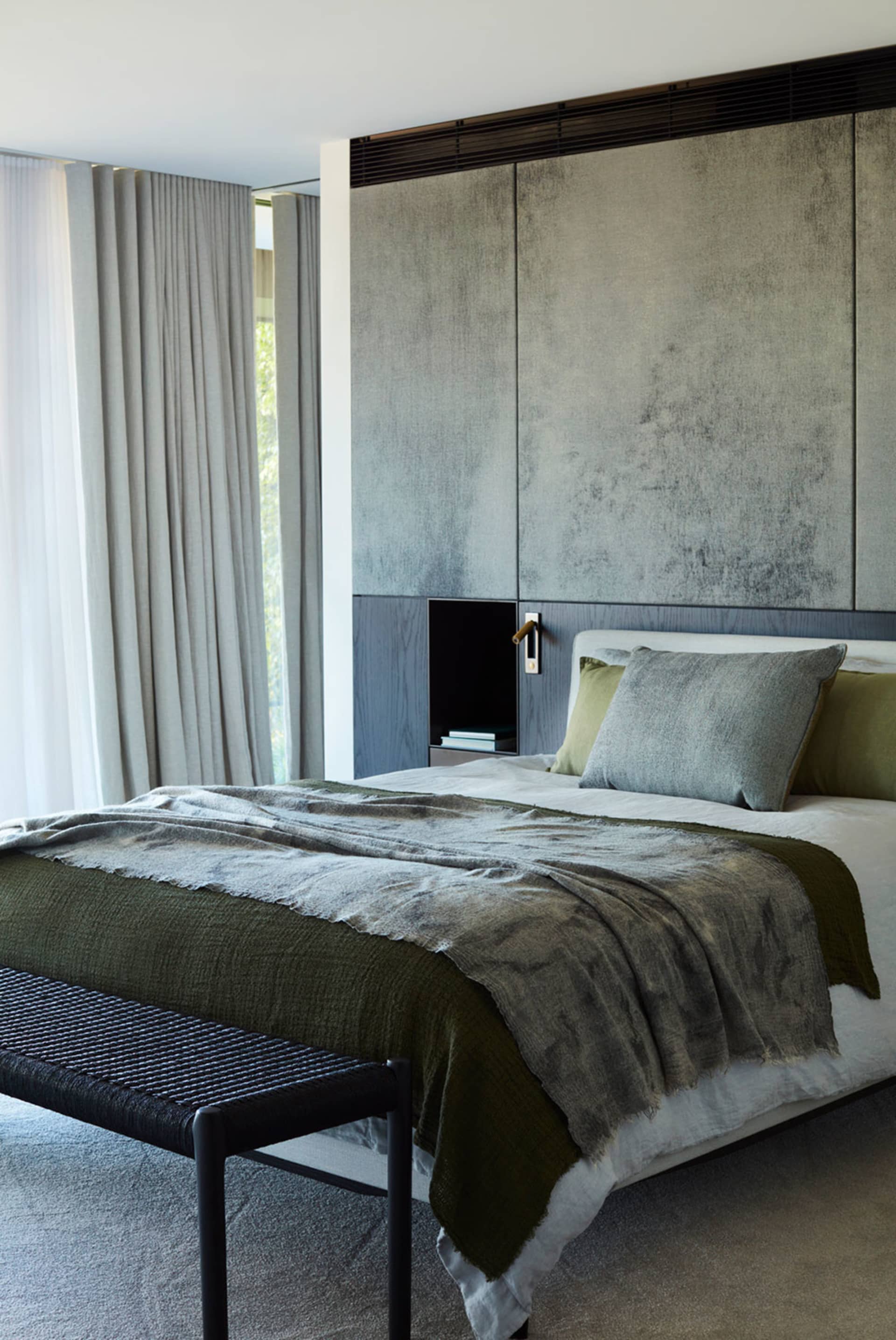 A minimalist bedroom featuring fabric bedding, a wooden bed frame, and a metal side table.