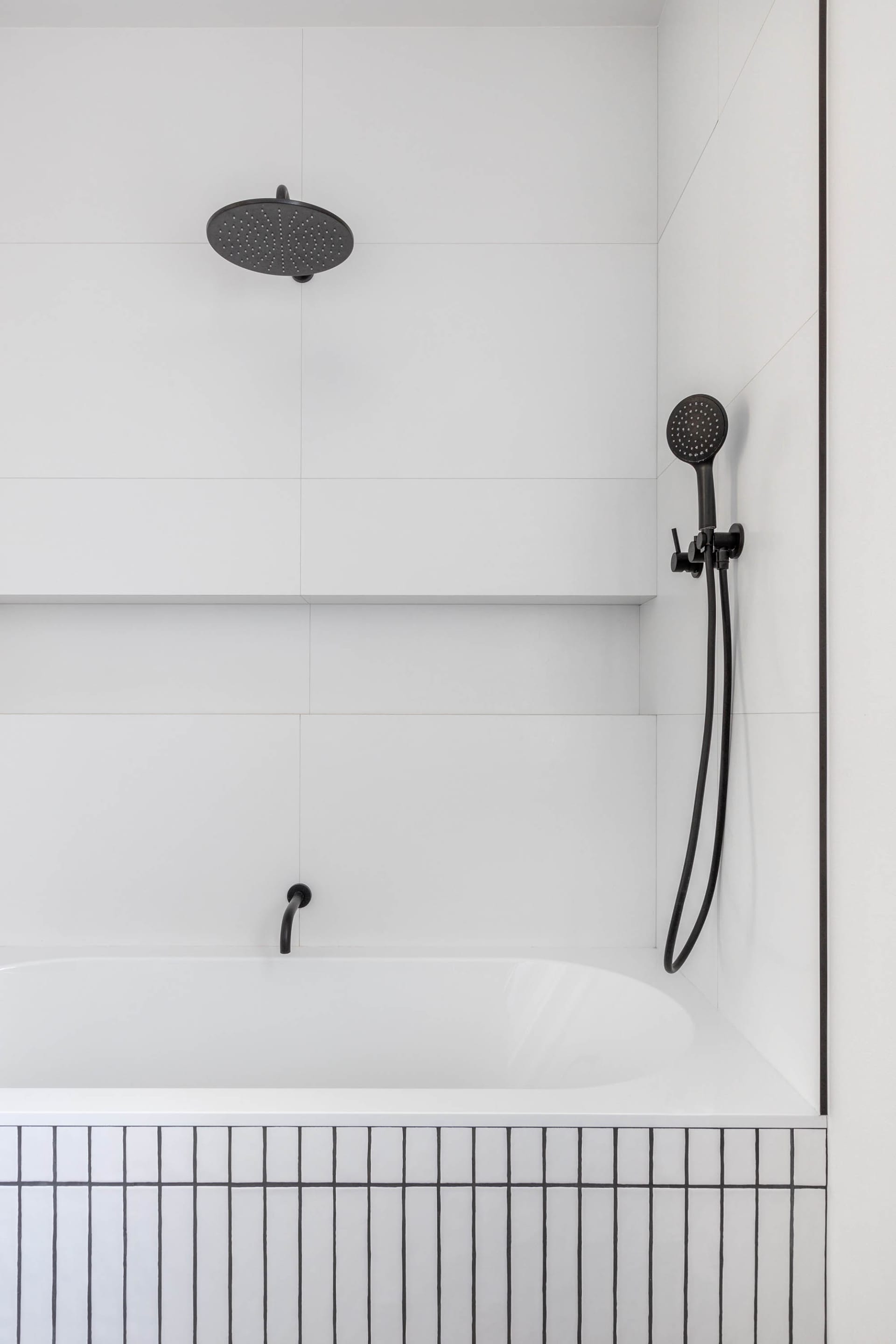 Modern minimalist bathroom with white tile walls and black fixtures.
