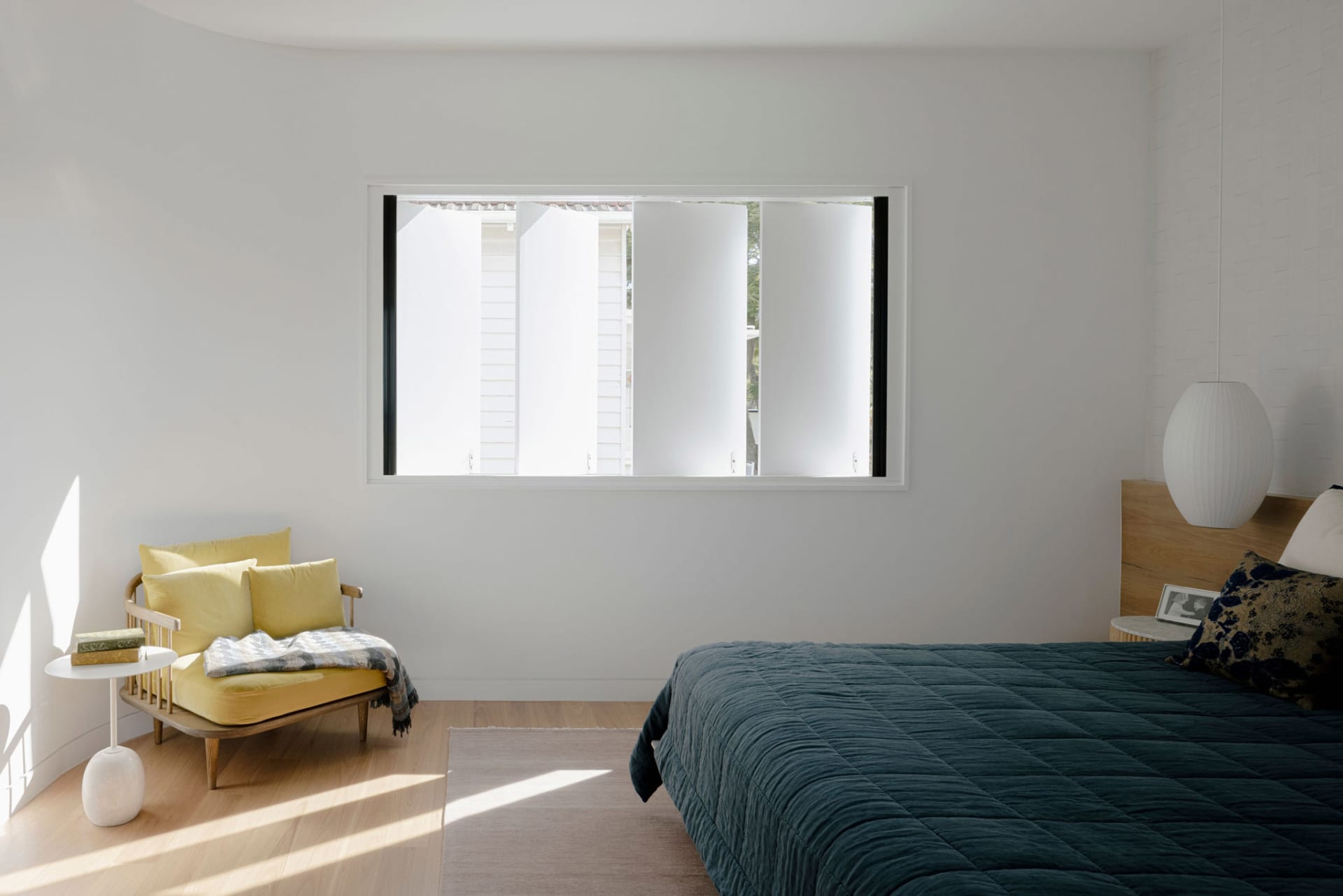 A minimalist bedroom featuring wood, fabric, and metal materials.