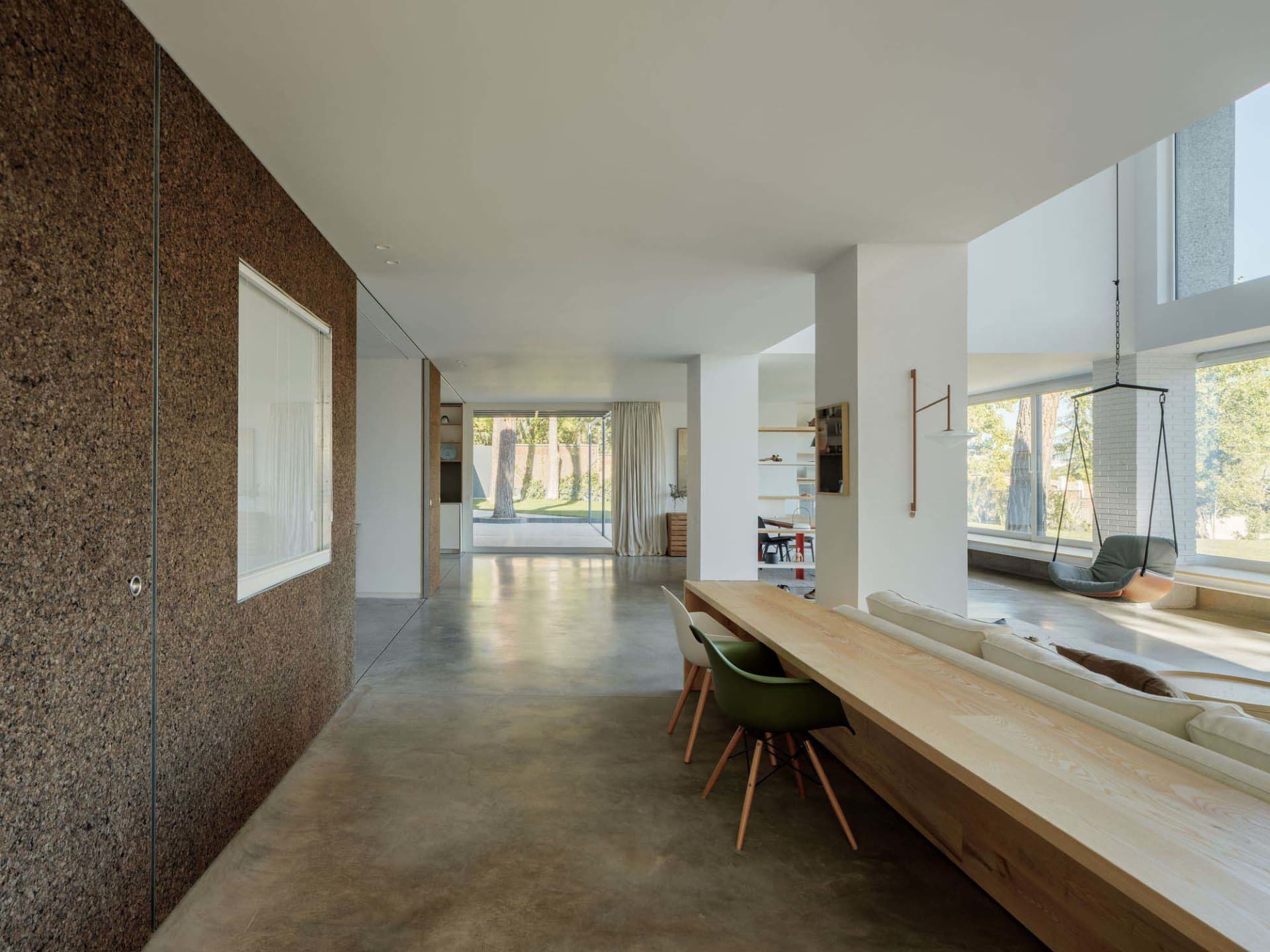 A spacious, modern residential interior featuring minimalist design, concrete flooring, and ample natural light, with a minim
