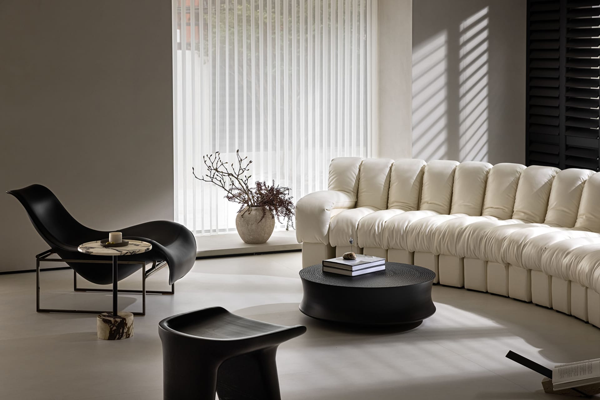 A modern living room with a white fabric sectional sofa, black marble coffee table, and black chair in front of a large windo