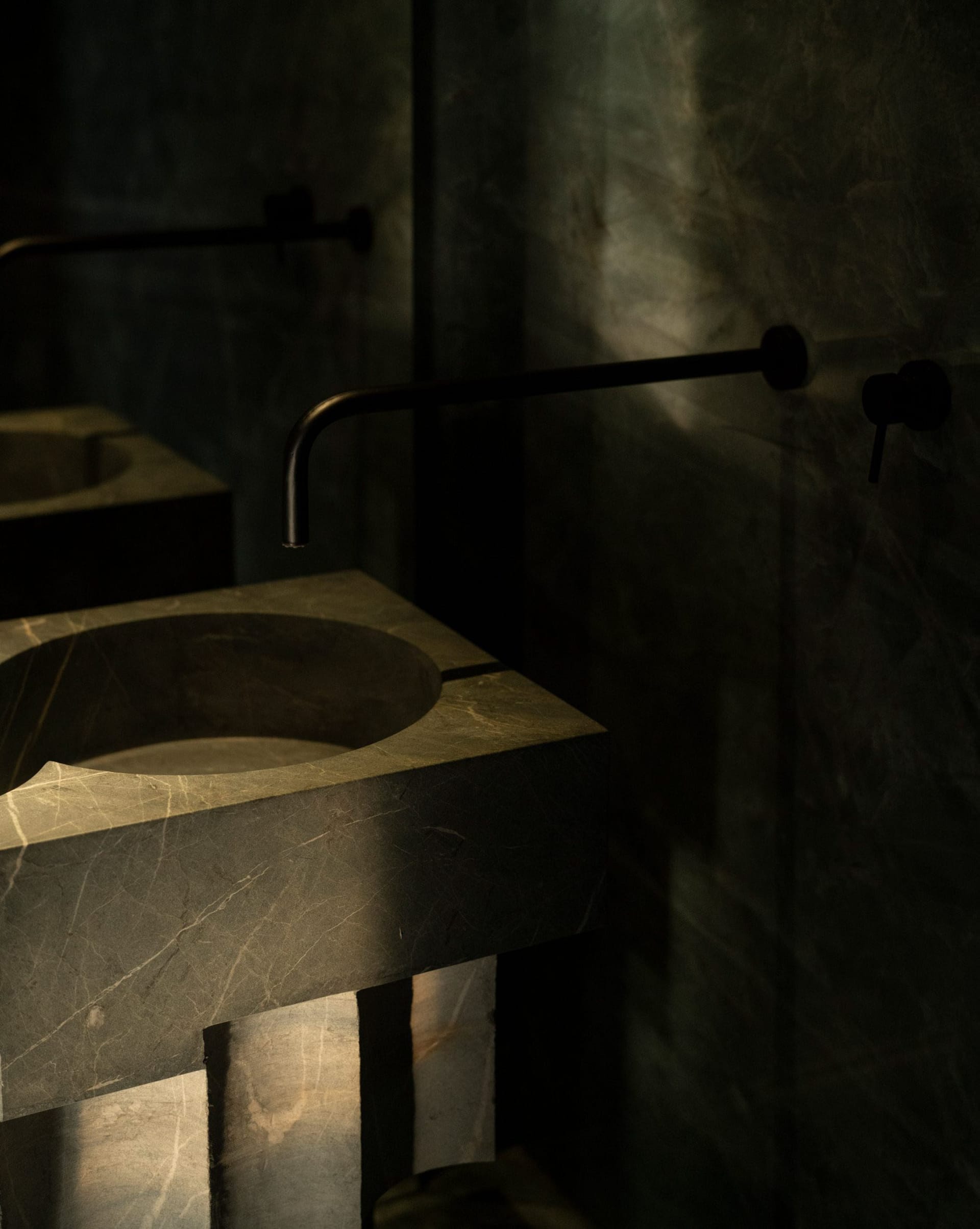 A modern bathroom featuring a stone countertop sink with a geometric faucet.