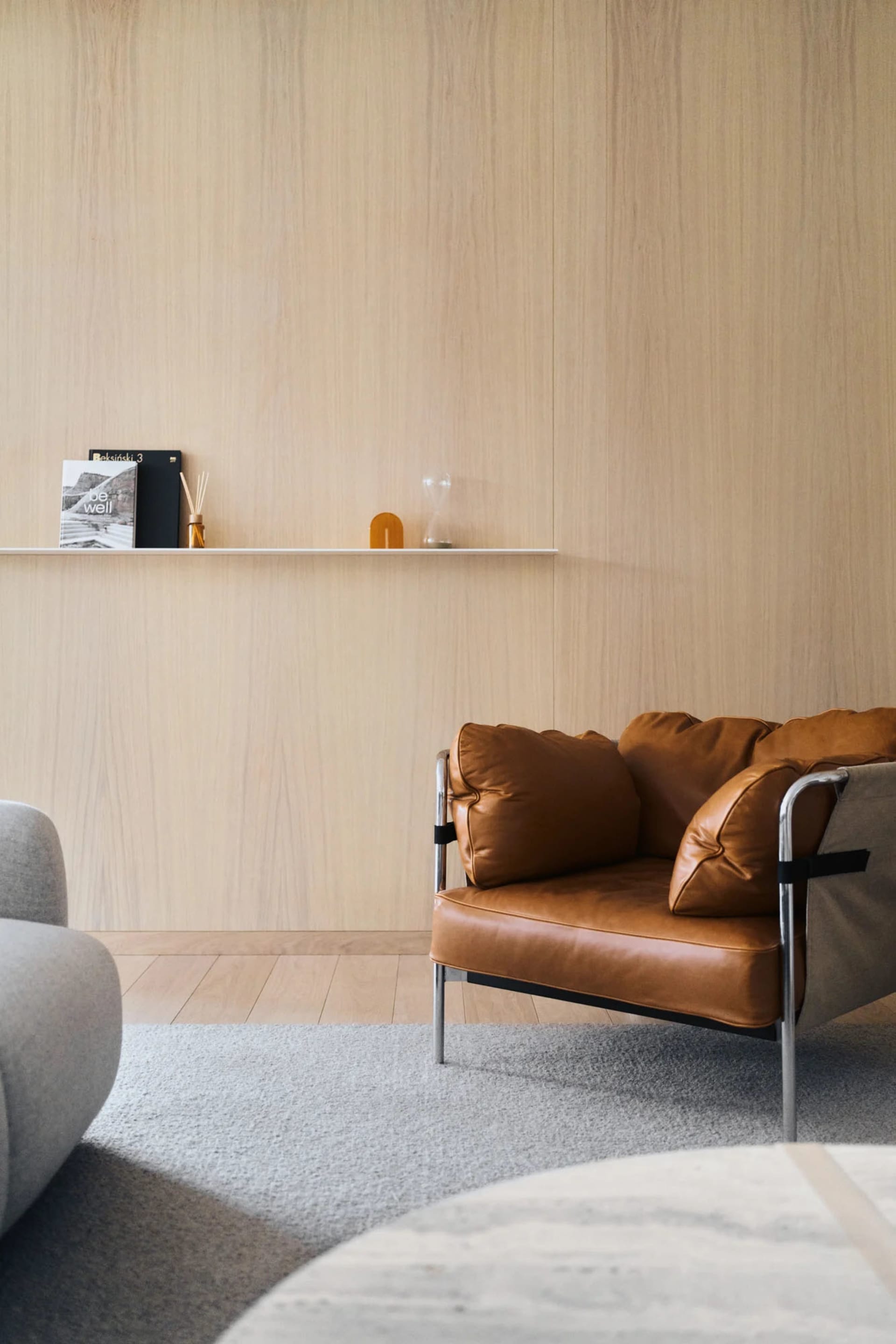 Living room with a minimalist design featuring a brown leather accent chair on a grey rug.
