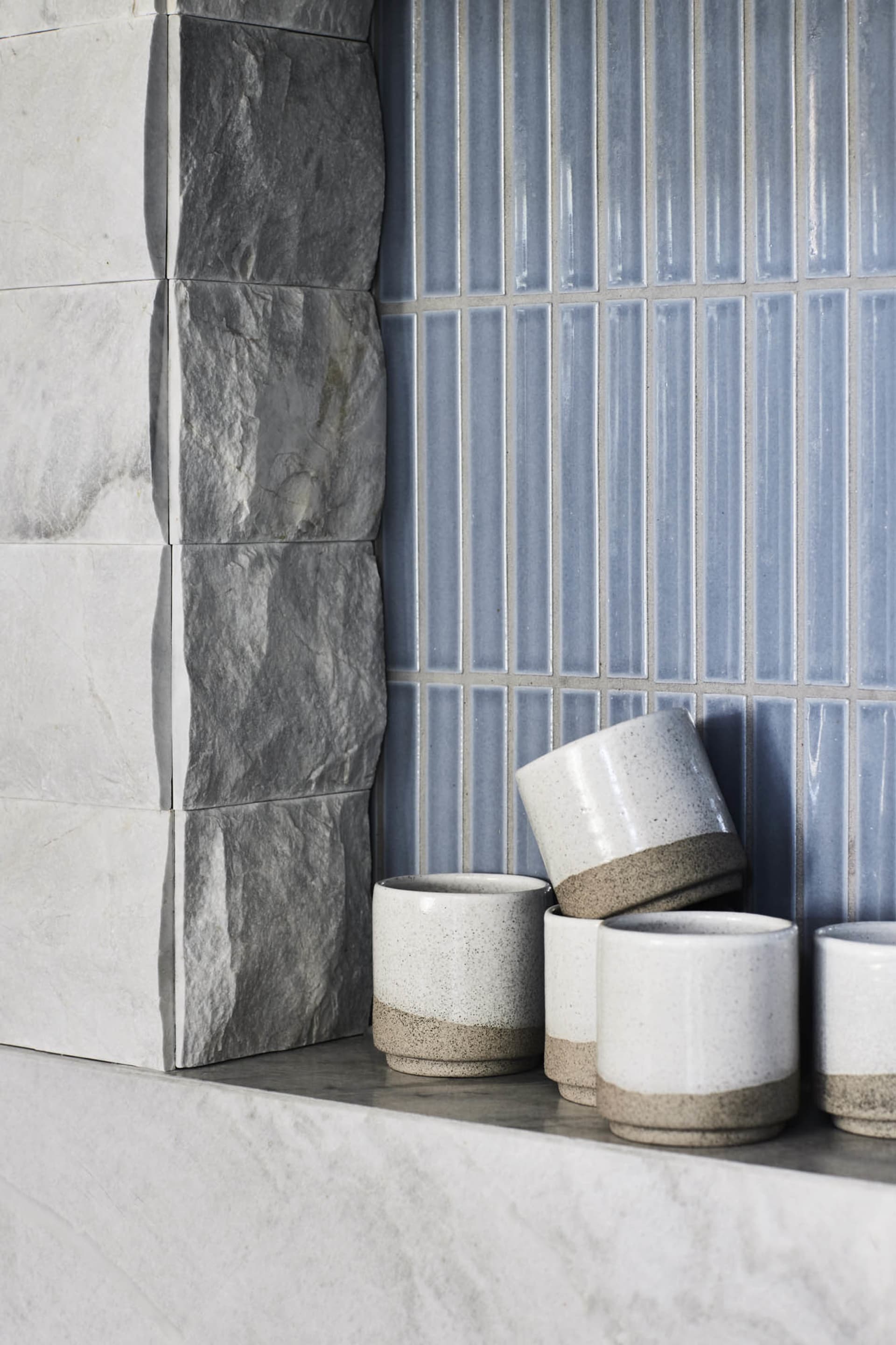 White ceramic cups with a brown base and blue ceramic tiles on a wall