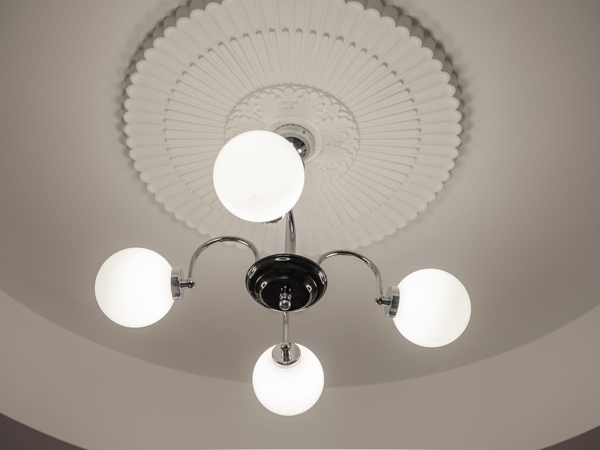 A minimalist ceiling light fixture with metal elements against a plain background.
