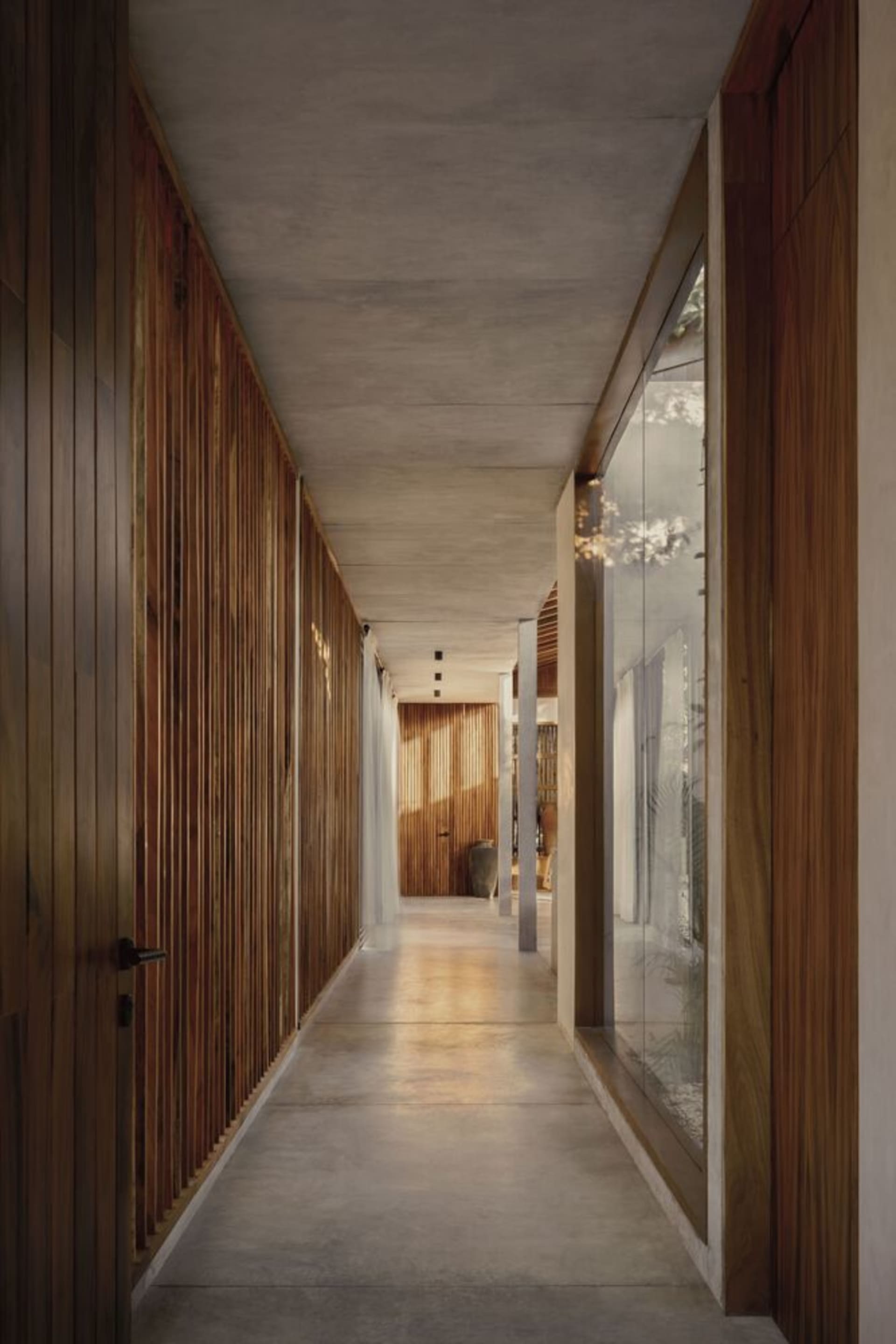 A modern residential hallway featuring wooden-paneled walls and a concrete floor