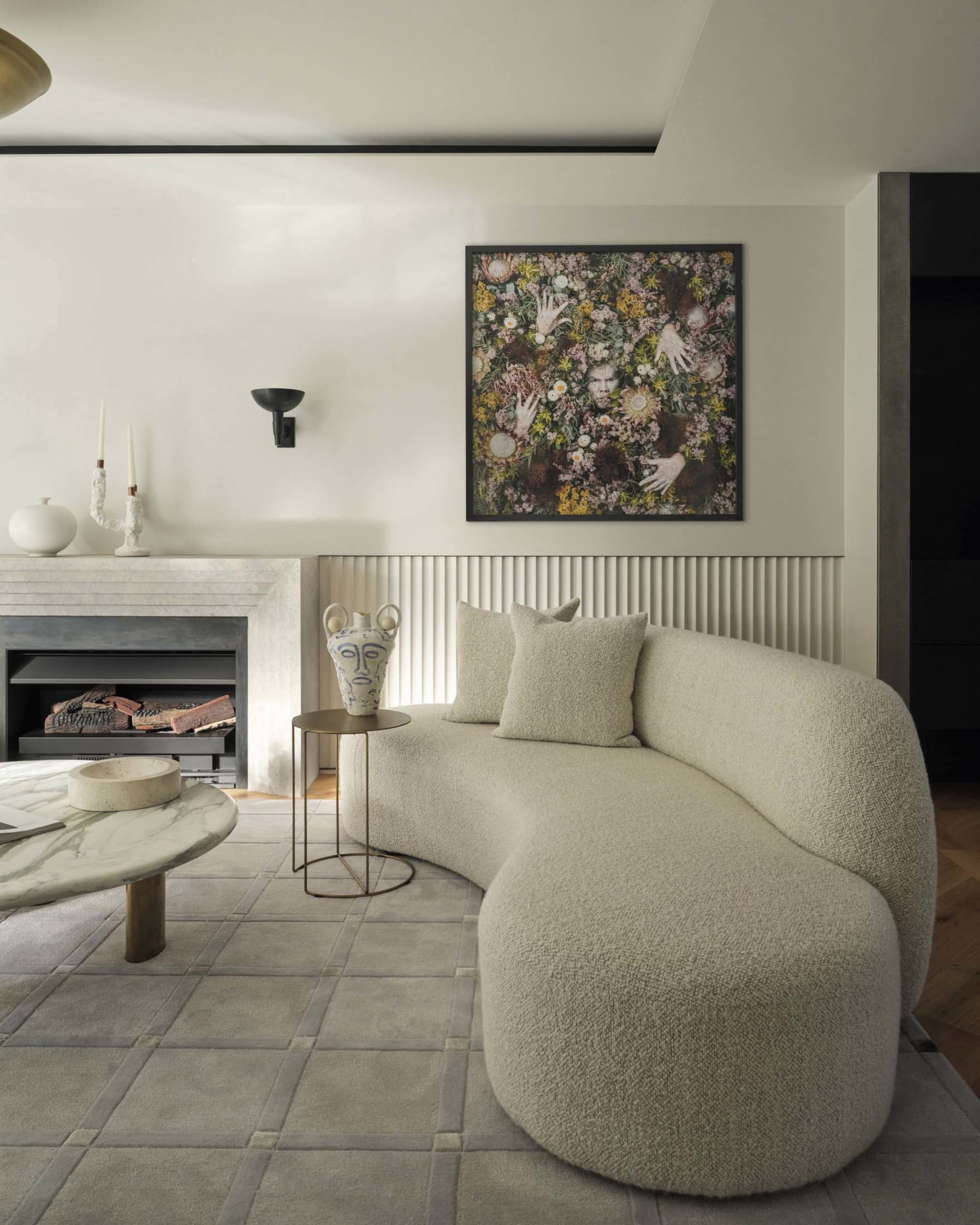 A modern living room with curved sofa, fireplace, and abstract floral art.