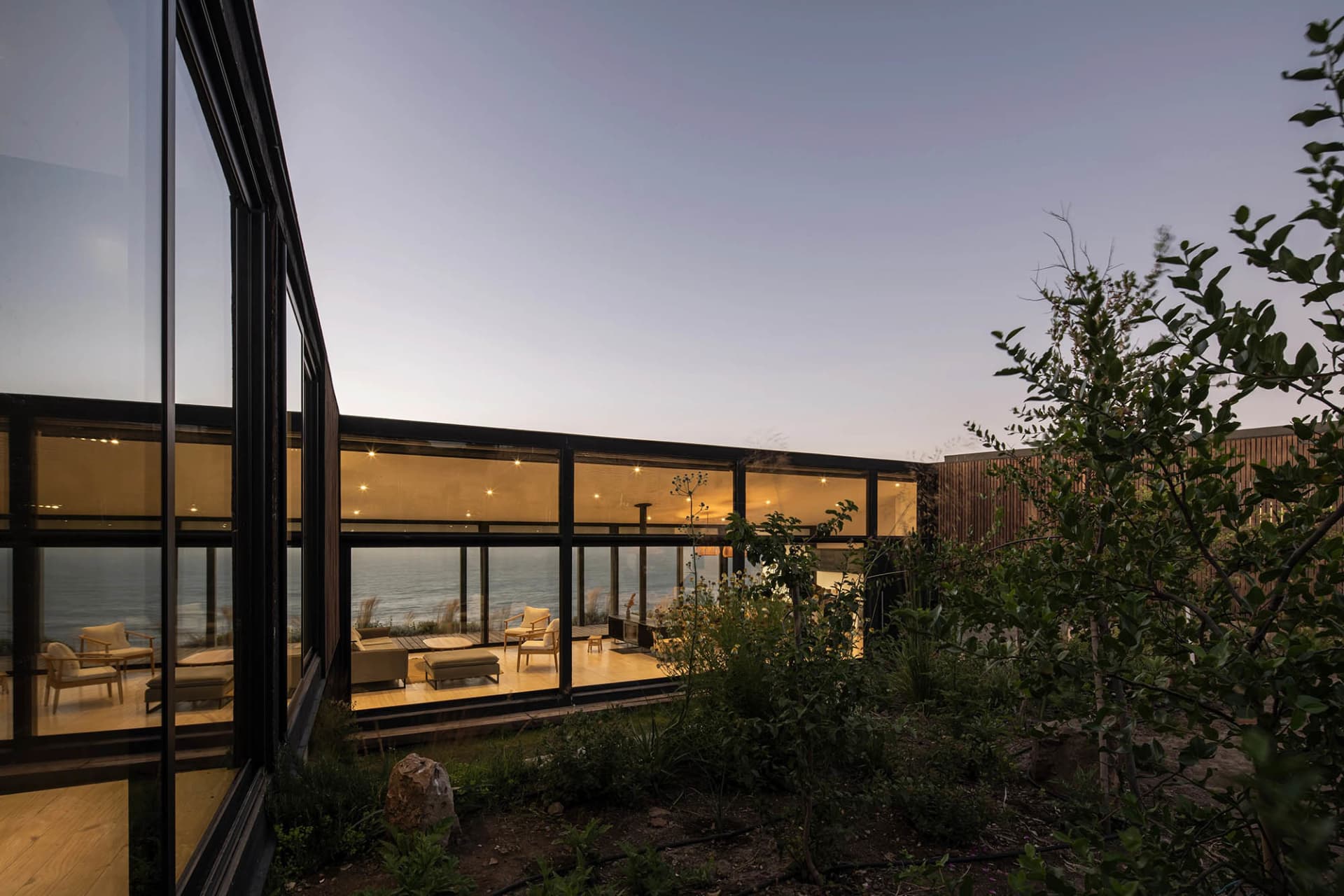 A modern residential interior featuring glass walls and wooden flooring.