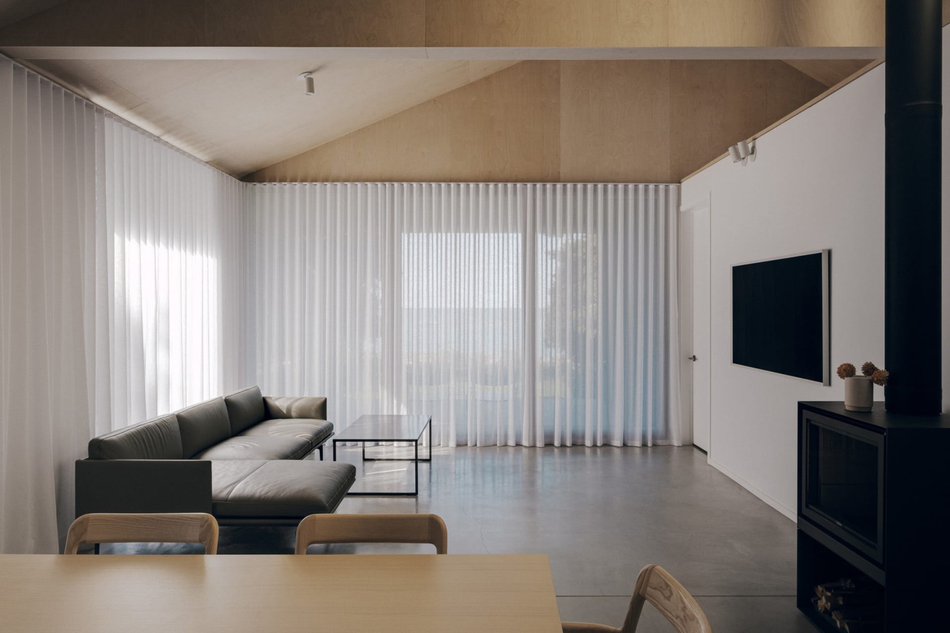 A modern minimalist living room with sheer curtains allowing natural light to filter in.