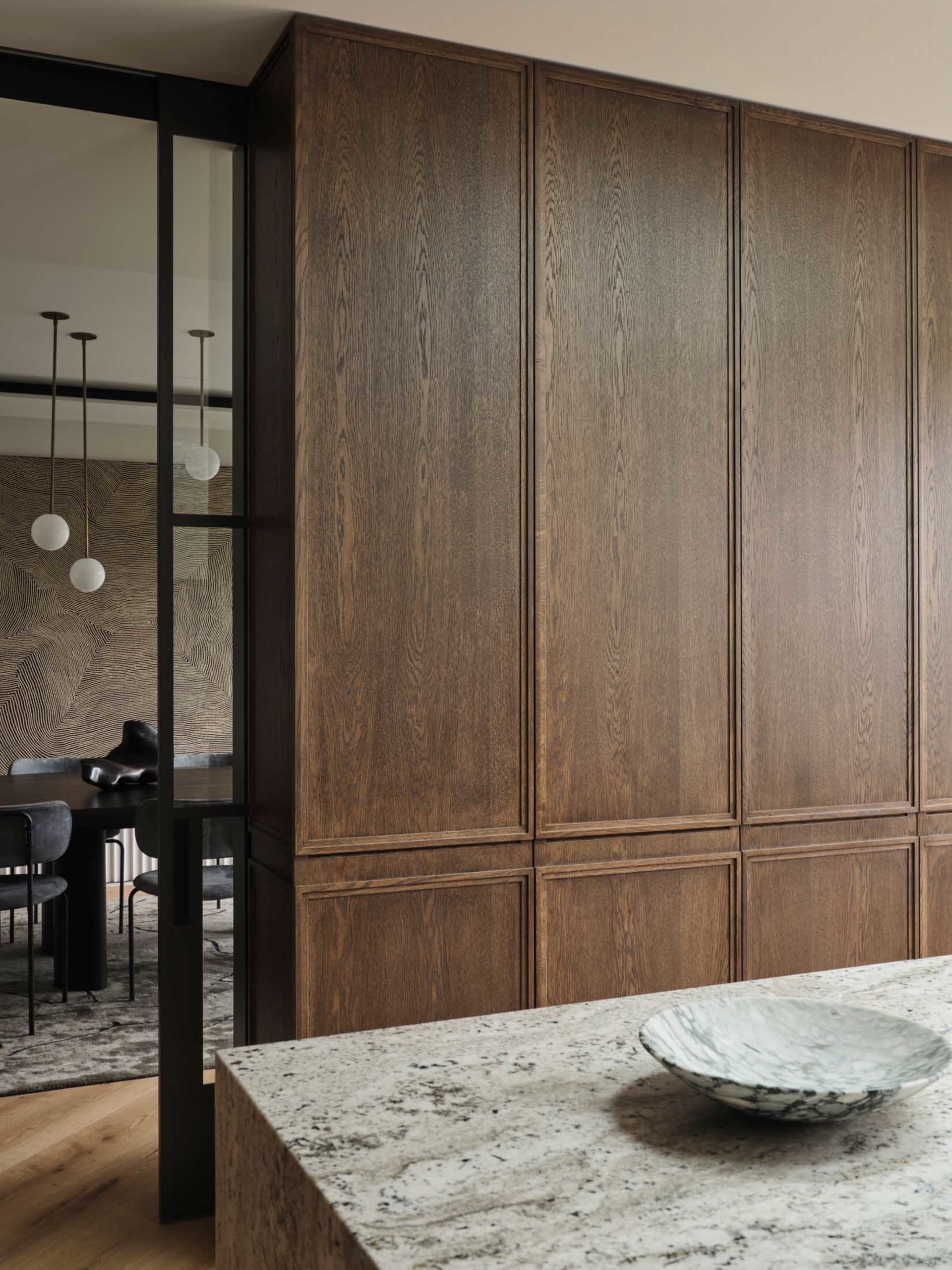 Modern residential interior with dark wood cabinets, marble countertop, and glass sliding door.