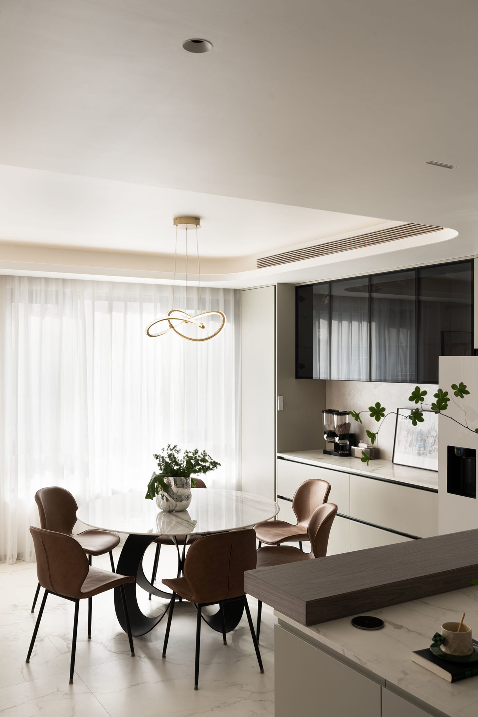 Modern kitchen with marble table, leather chairs, and floating glass cabinets.