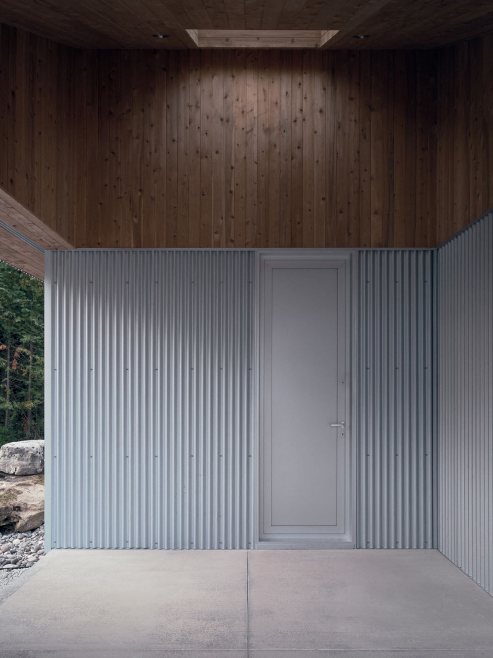 Modern minimalist entrance with corrugated metal materials and concrete floor.