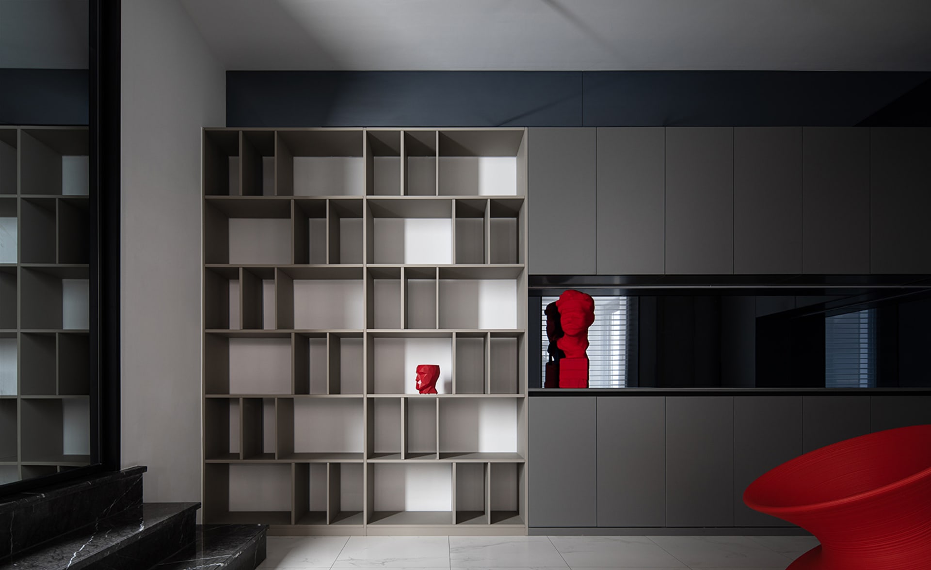 Modern library interior with wooden shelves and red sculptures.