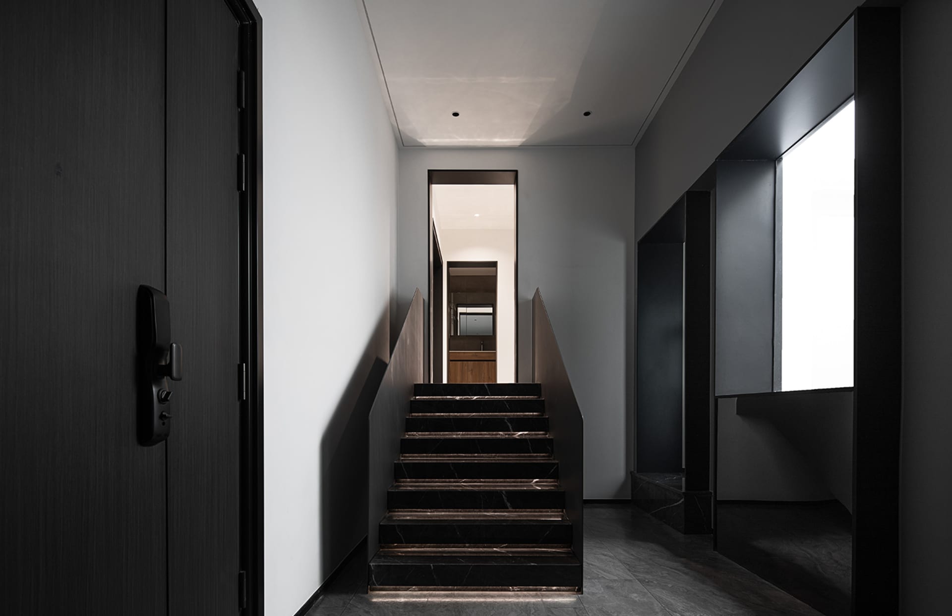 Modern minimalist staircase with black marble steps and black walls.