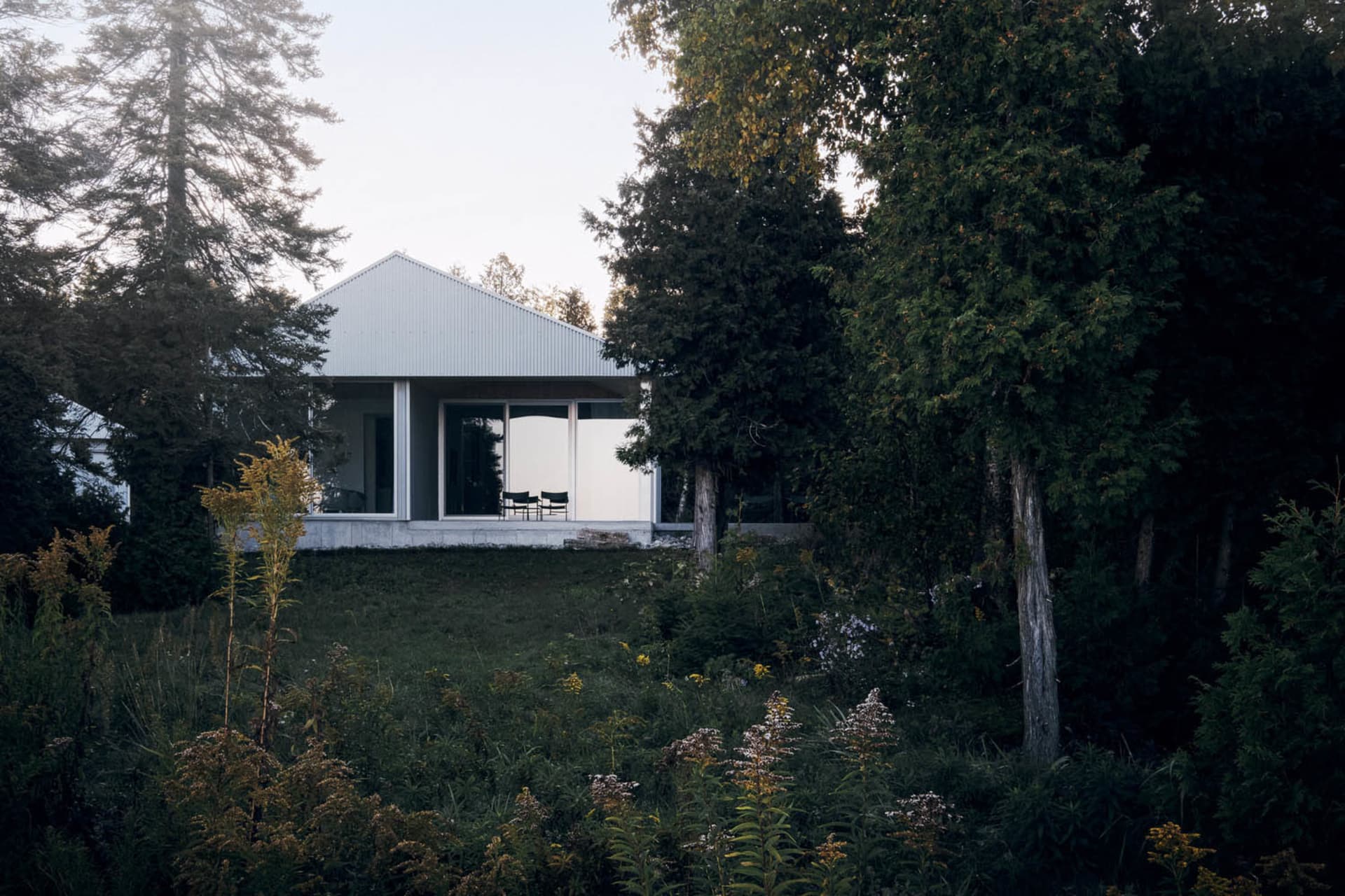 A modern house with a metal-clad exterior, featuring large windows and a minimalist design.