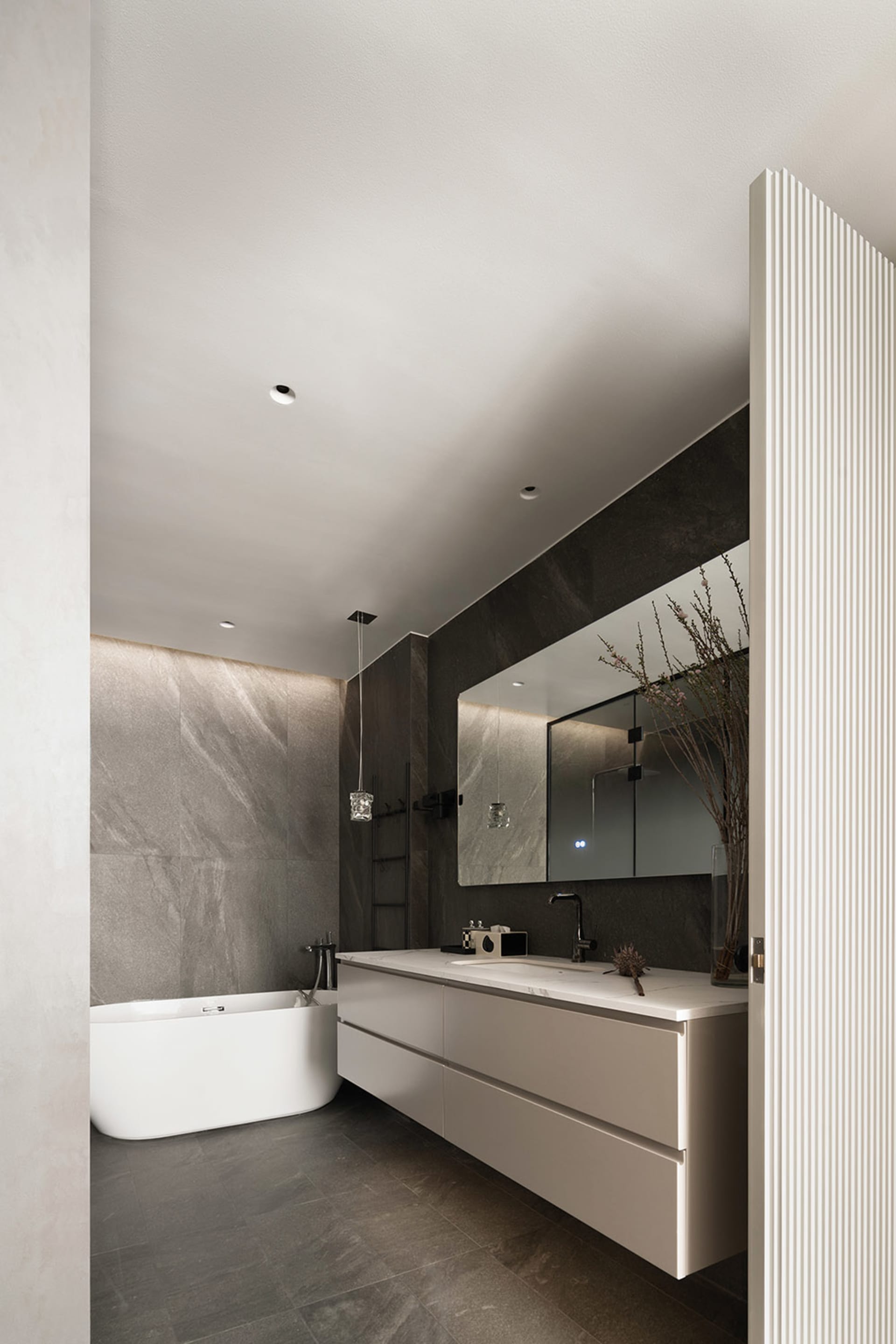 Photo of a modern bathroom interior with marble finishes, a freestanding bathtub, and a floating vanity.