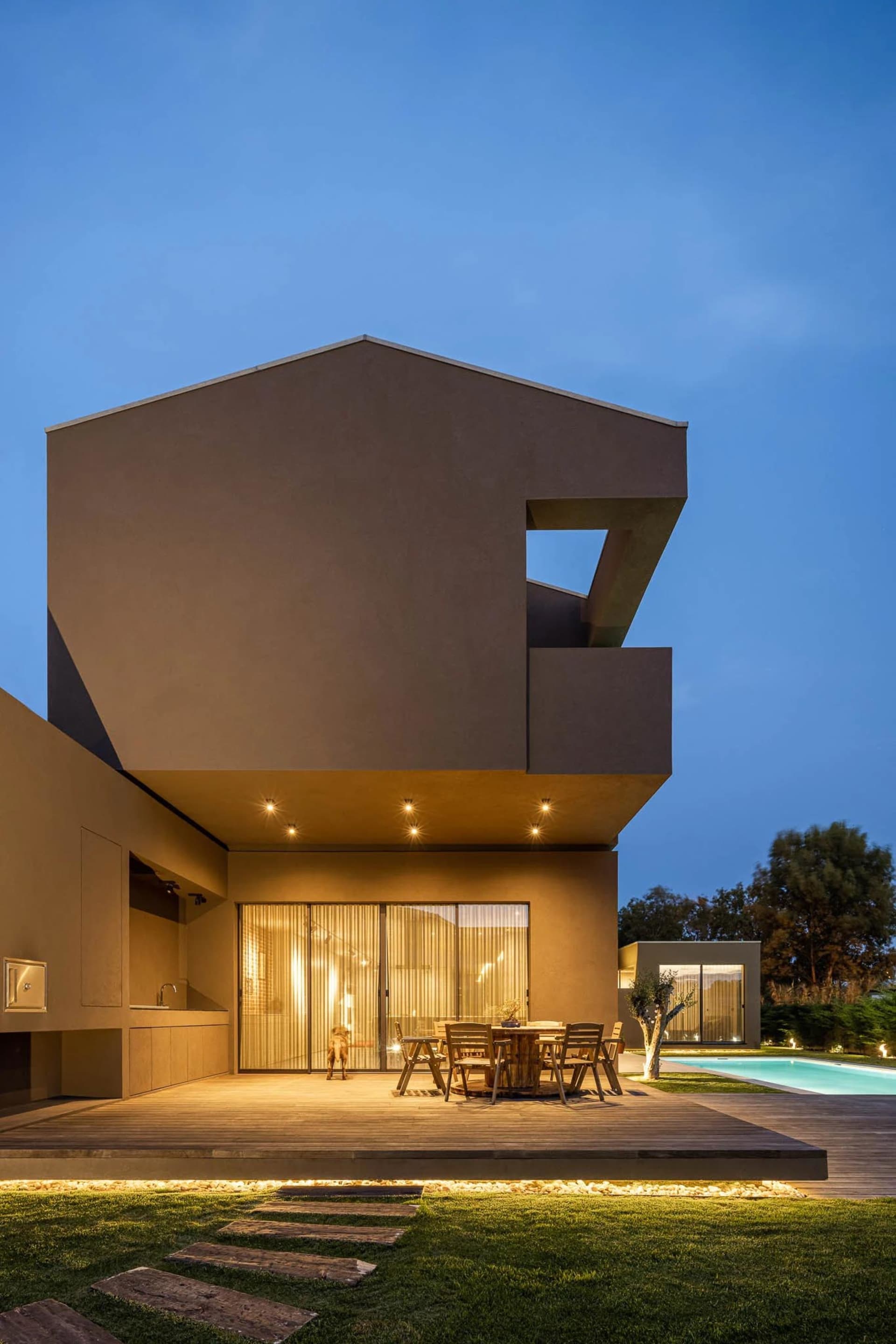 Modern house exterior with wood, concrete, and glass materials at dusk.