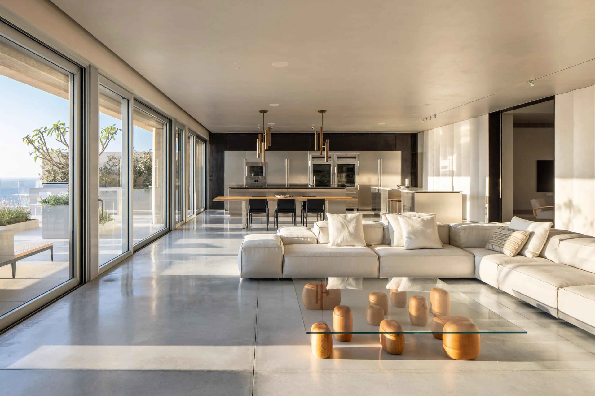Modern minimalist living room with concrete floor and large windows.