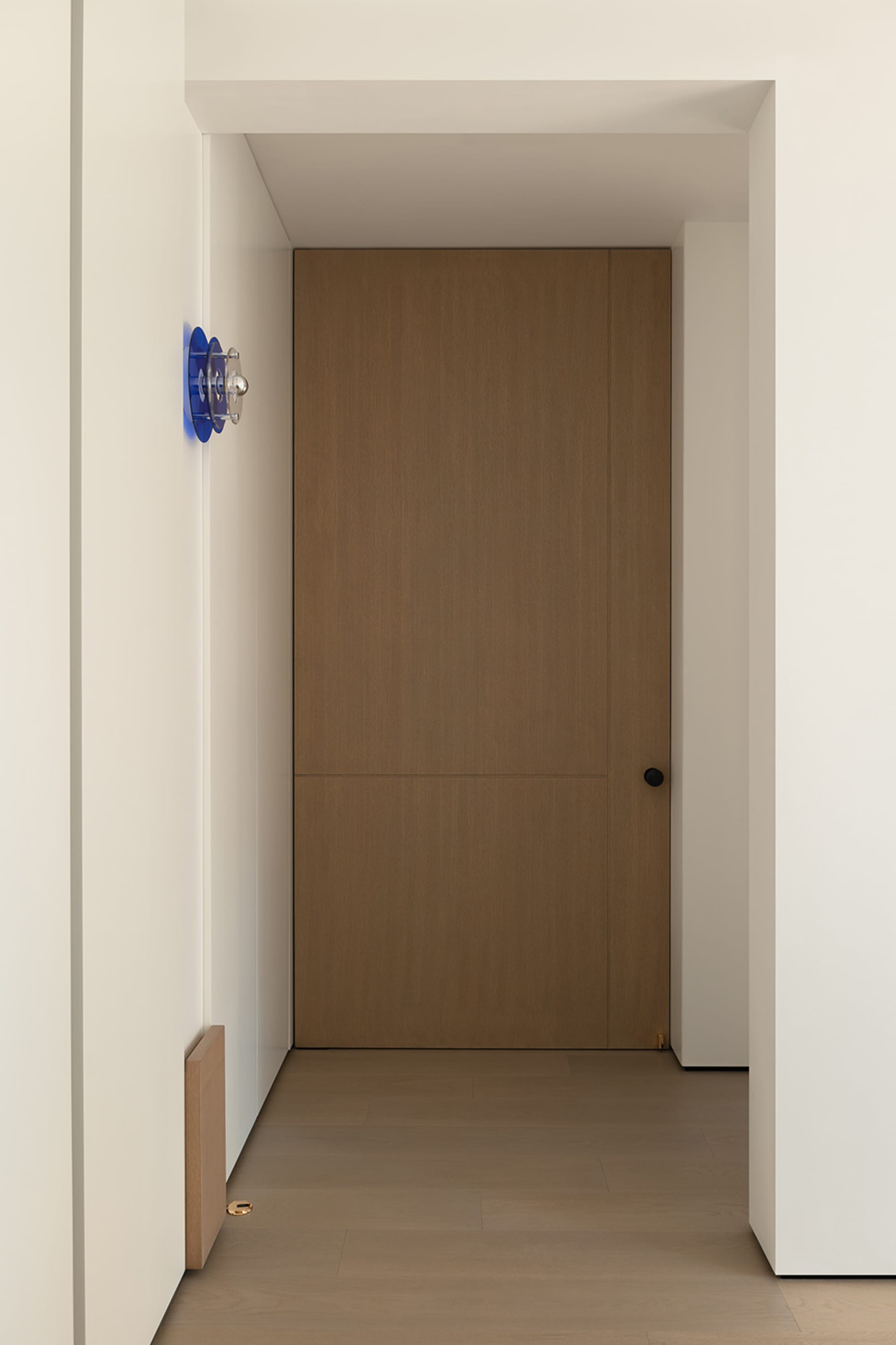 A modern, minimalist wooden door with a simple knob and small window.