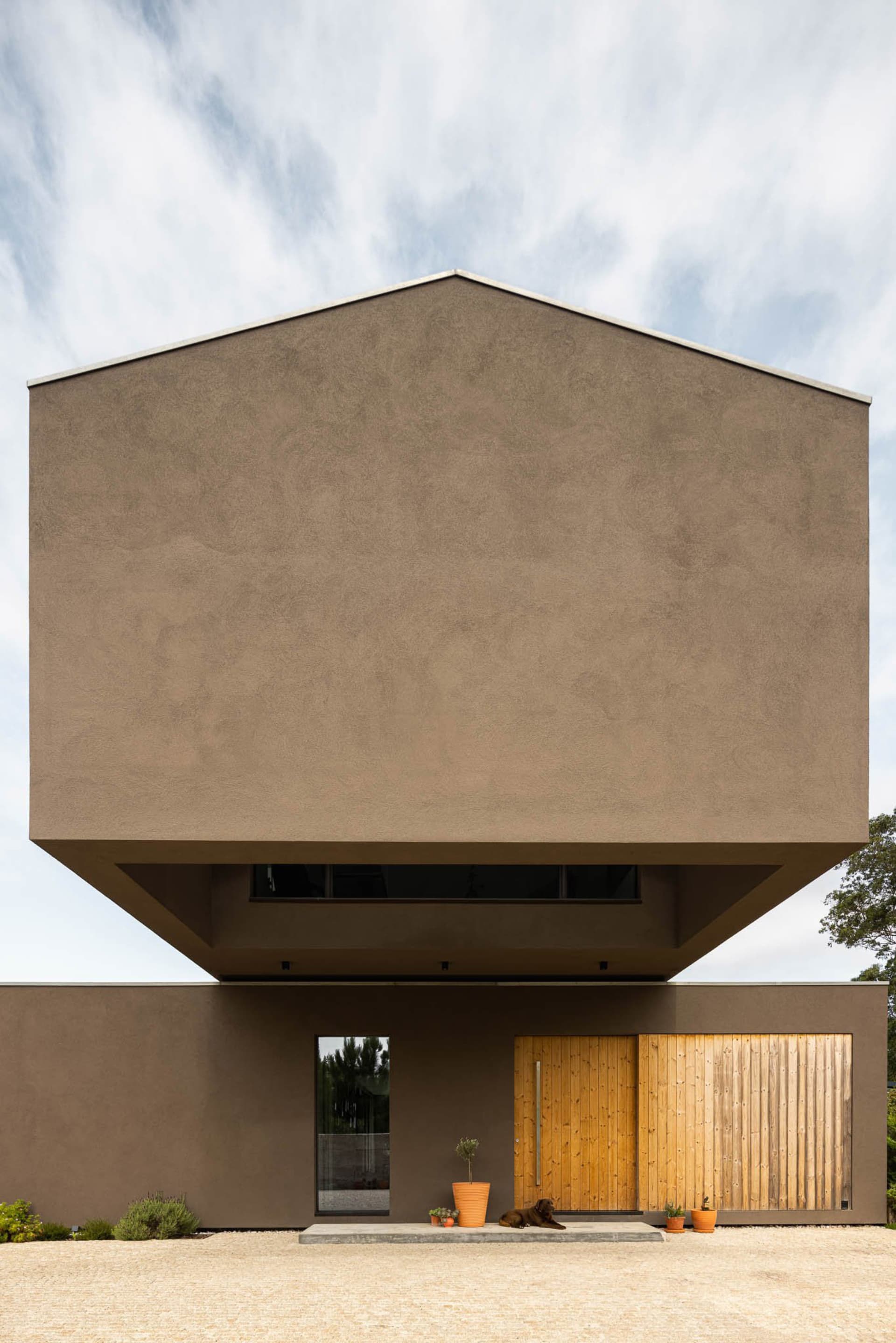 Modern house with stucco facade, concrete roof, and wooden door and window frames.