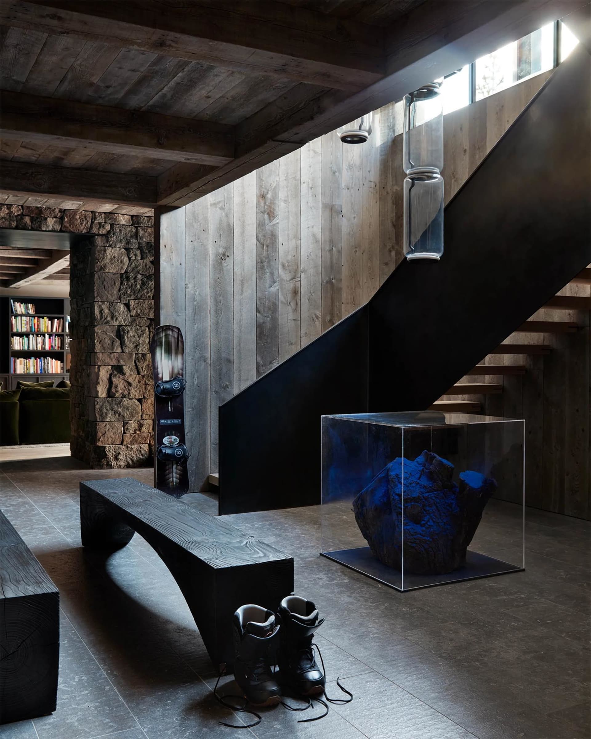 Modern industrial interior featuring wooden bench, concrete floor, stone accent wall, metal railings, and concrete steps. Inc