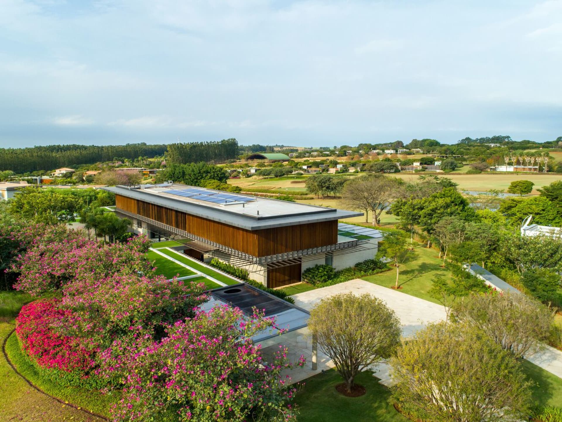 A modern residential home featuring glass walls, wooden accents, and concrete patio.