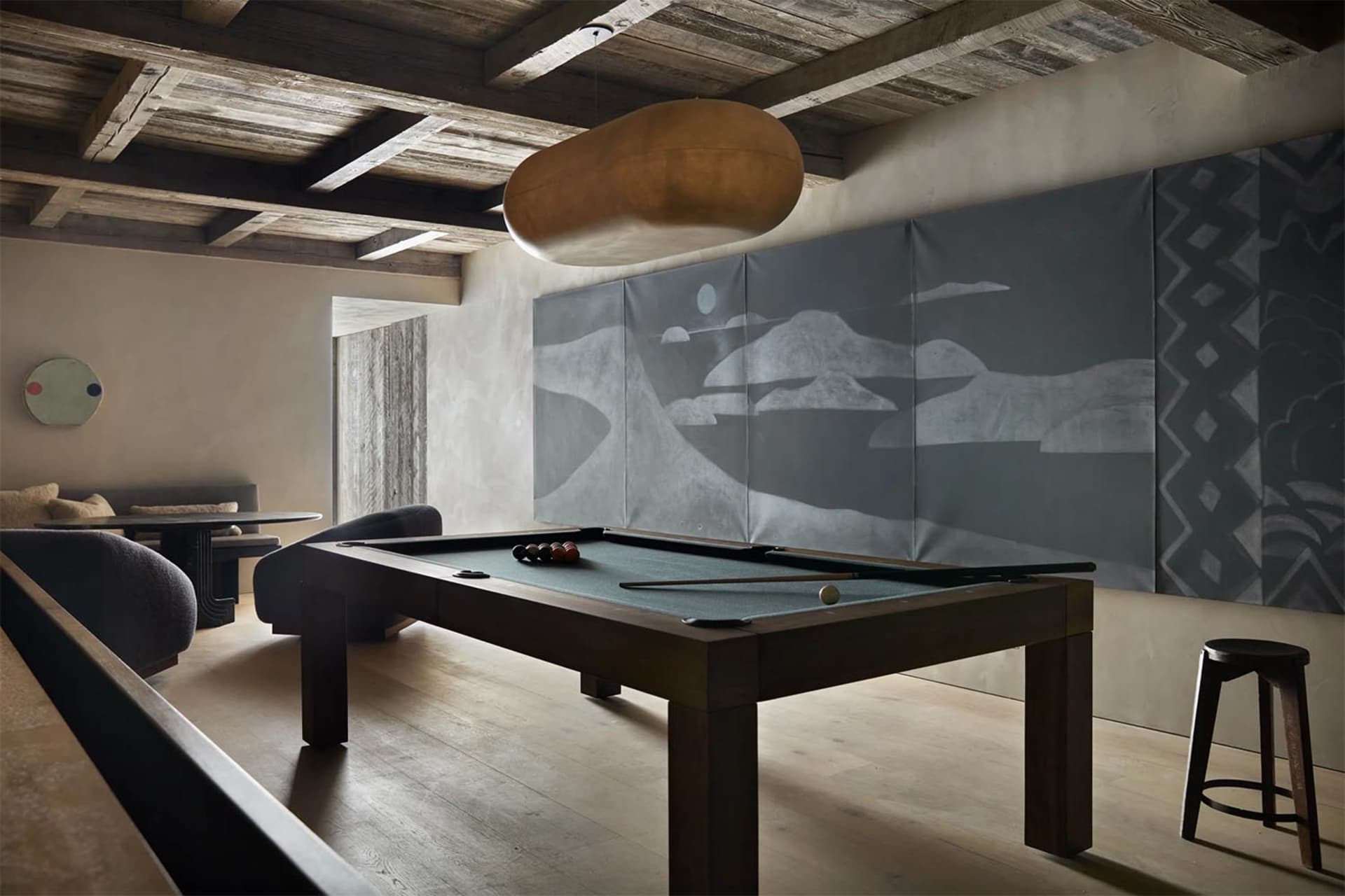 A rustic-style game room featuring a wooden pool table and textured wall art.