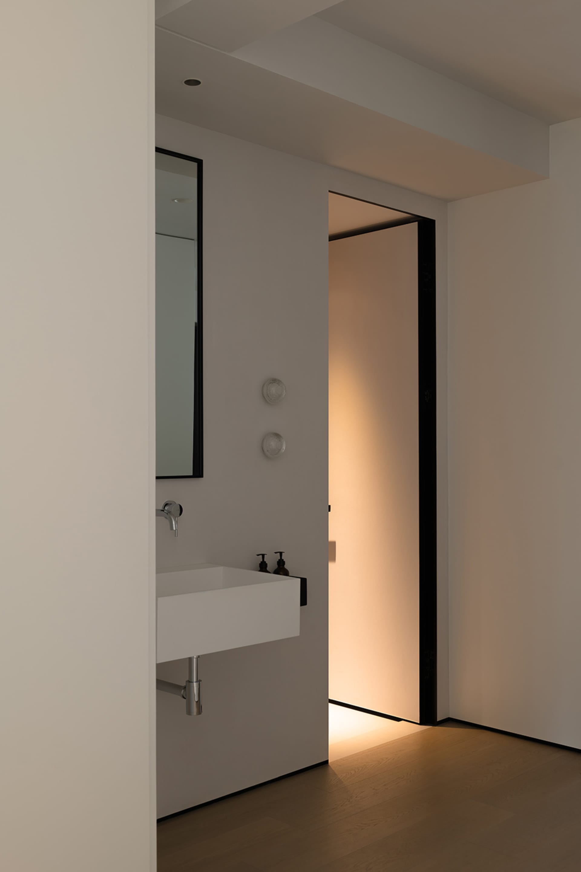 Modern minimalist bathroom featuring a concrete sink and mirror with a glass door.
