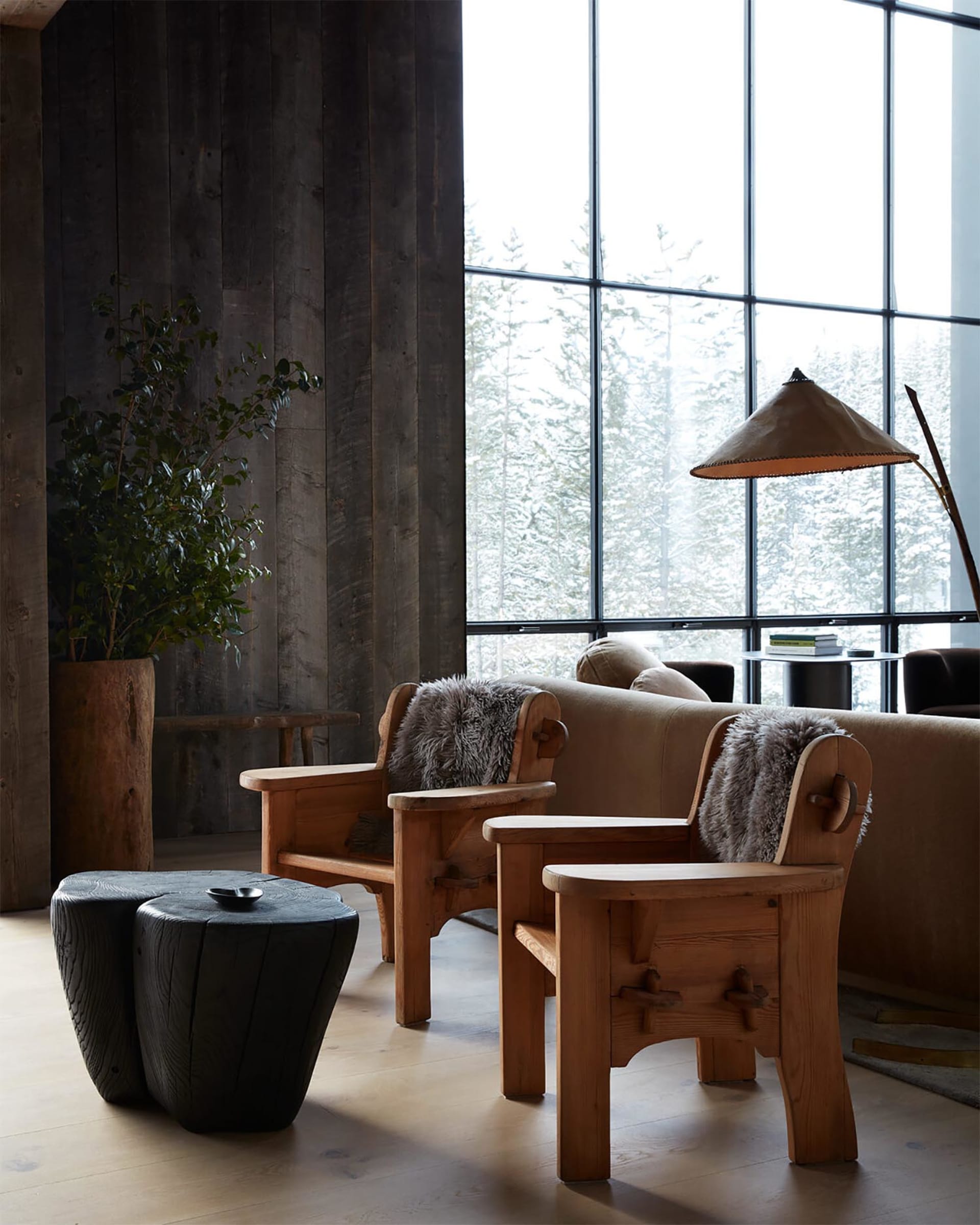Industrial-style residential living room featuring wooden furniture and large windows with a snowy landscape view.