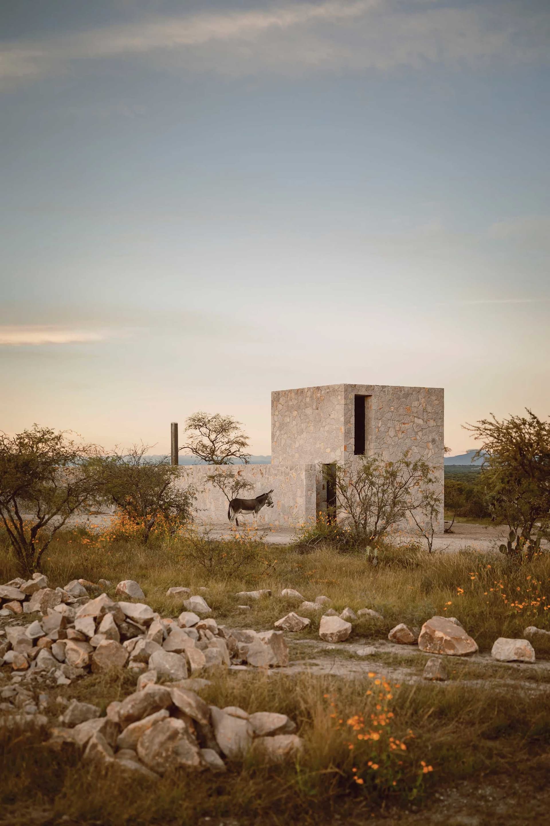 A minimalist building constructed of stone materials with a simple, open design.