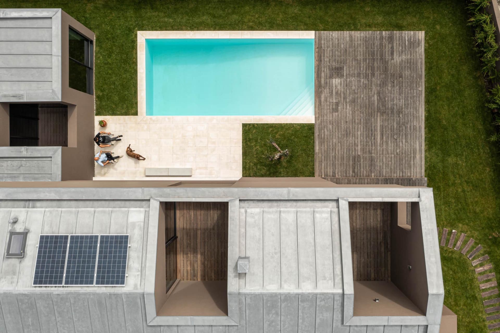 A modern house with a concrete exterior features a swimming pool and deck area.