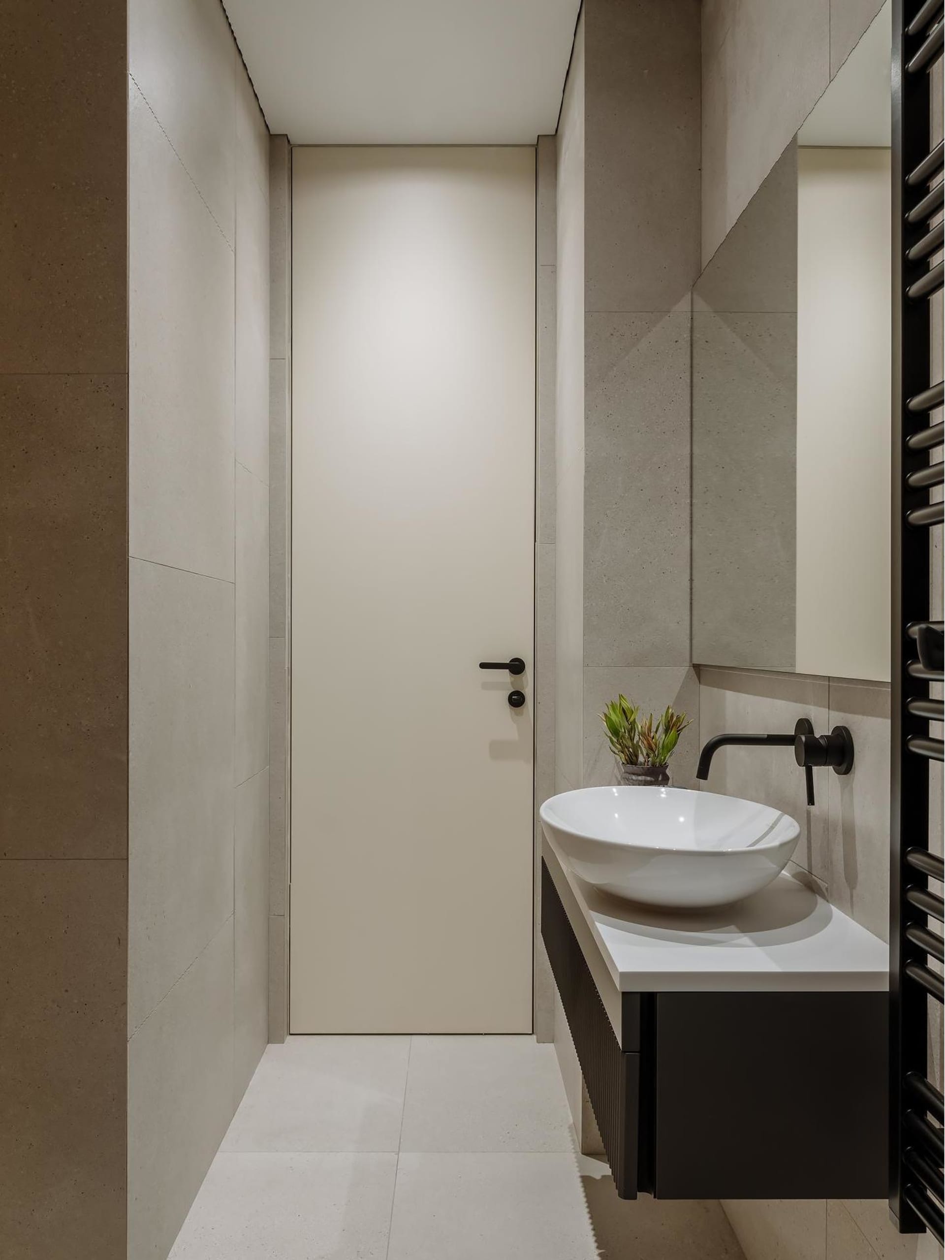 Modern minimalist bathroom with concrete walls and floor, white sink, and black accents.