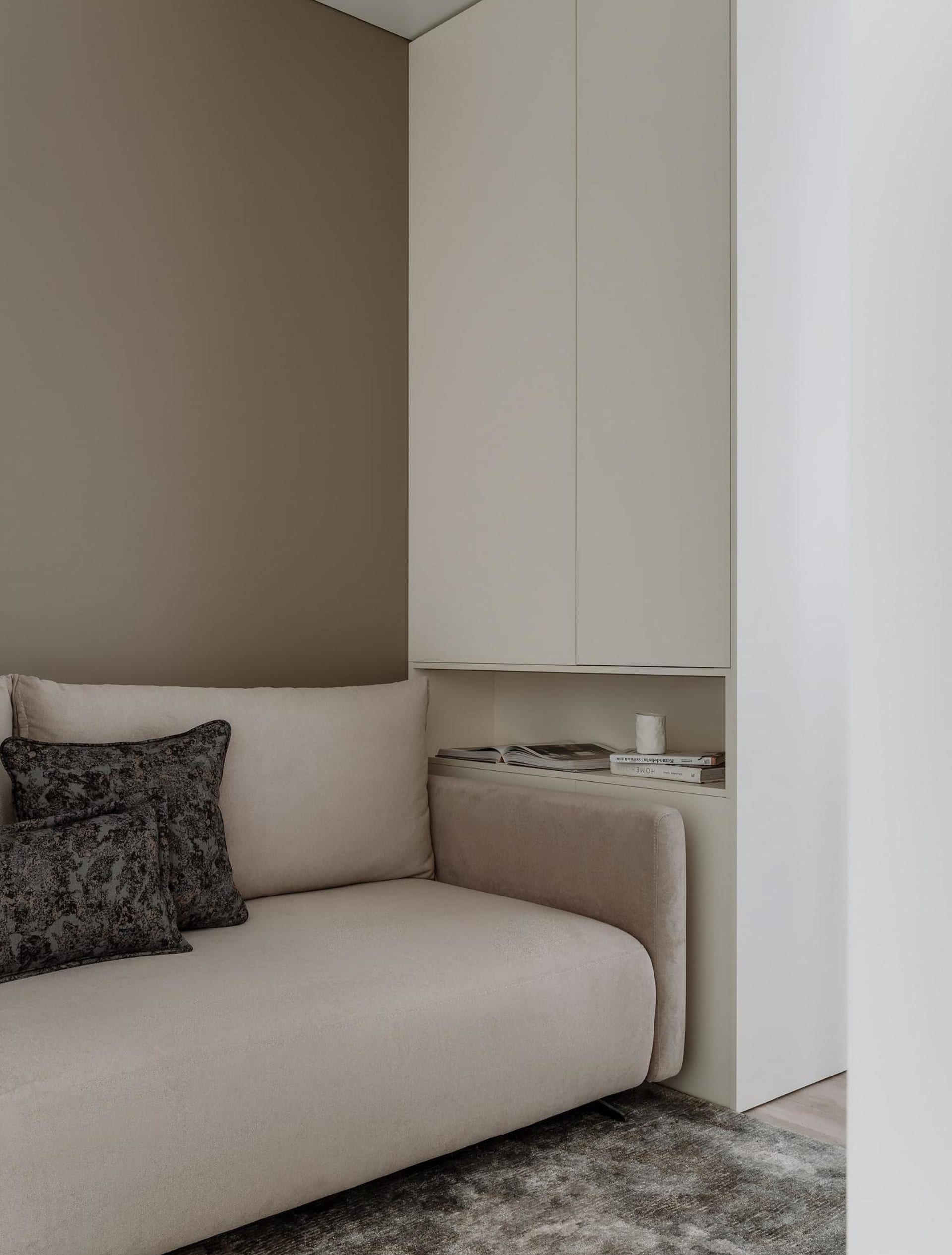 A modern minimalist living room with a beige sectional sofa adorned with patterned cushions, situated against a light-colored