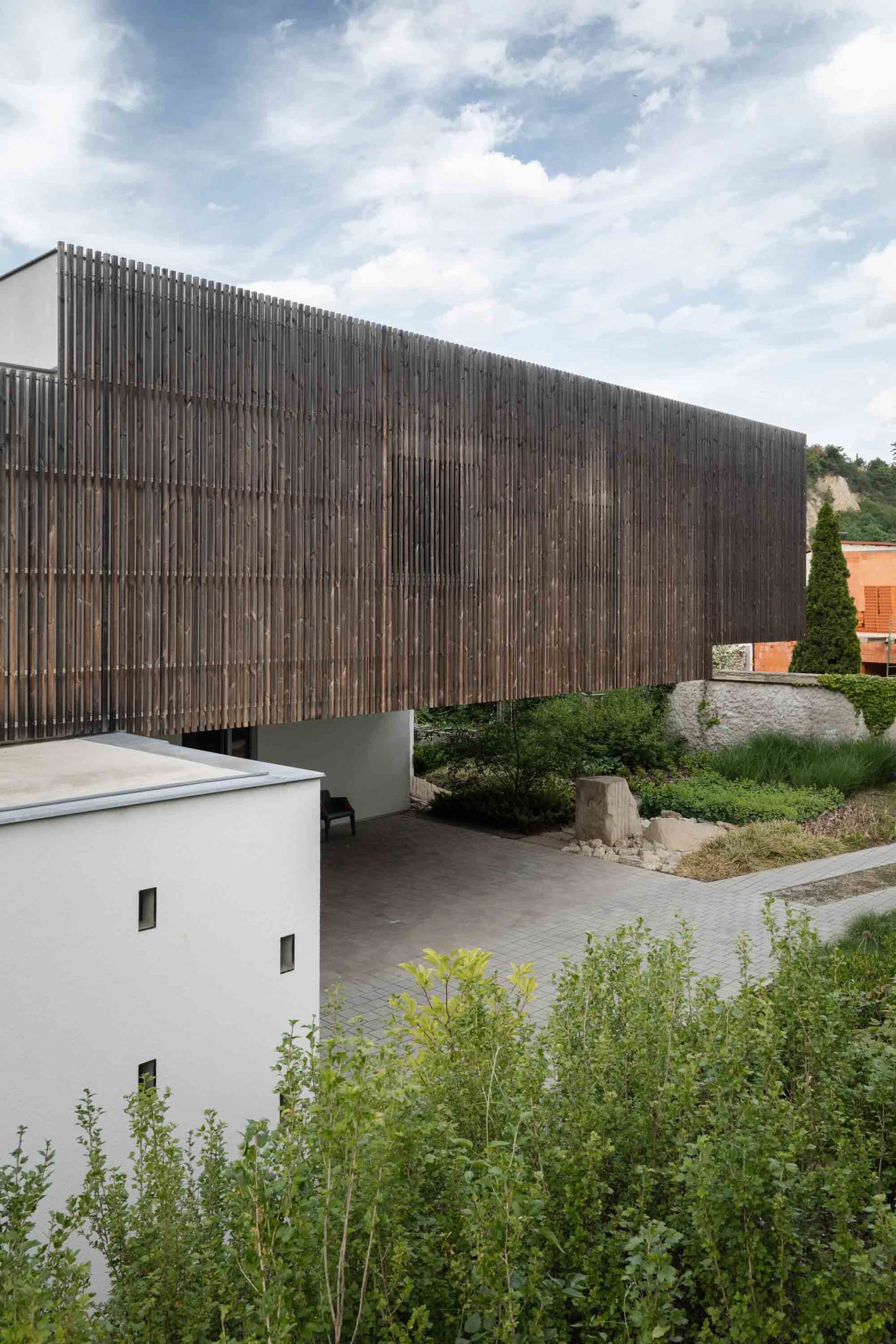 Modern architectural design featuring wooden fence and stone elements.