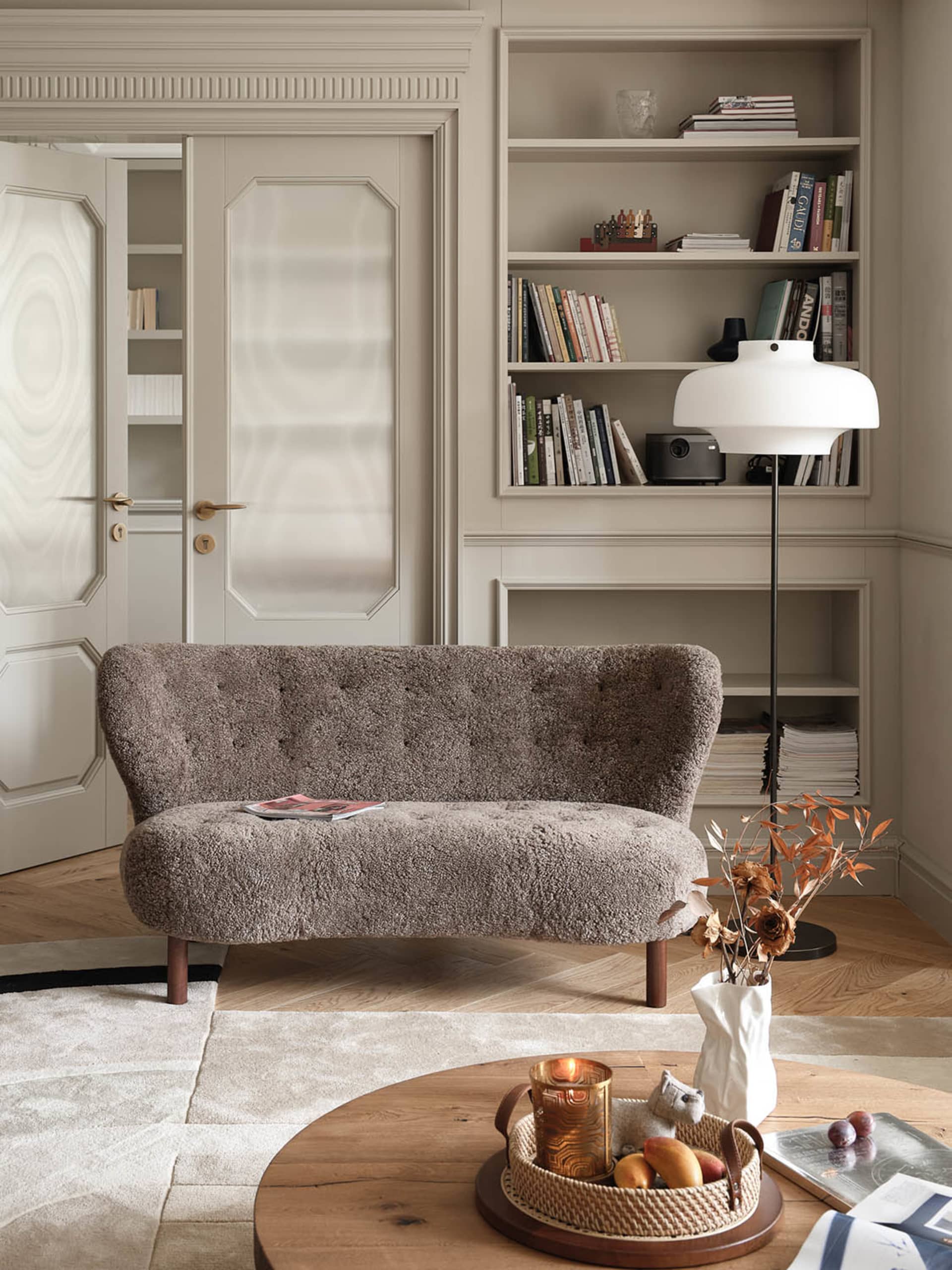 A cozy living room with a plush sofa, a wooden coffee table, and a bookshelf filled with books and decorative items.