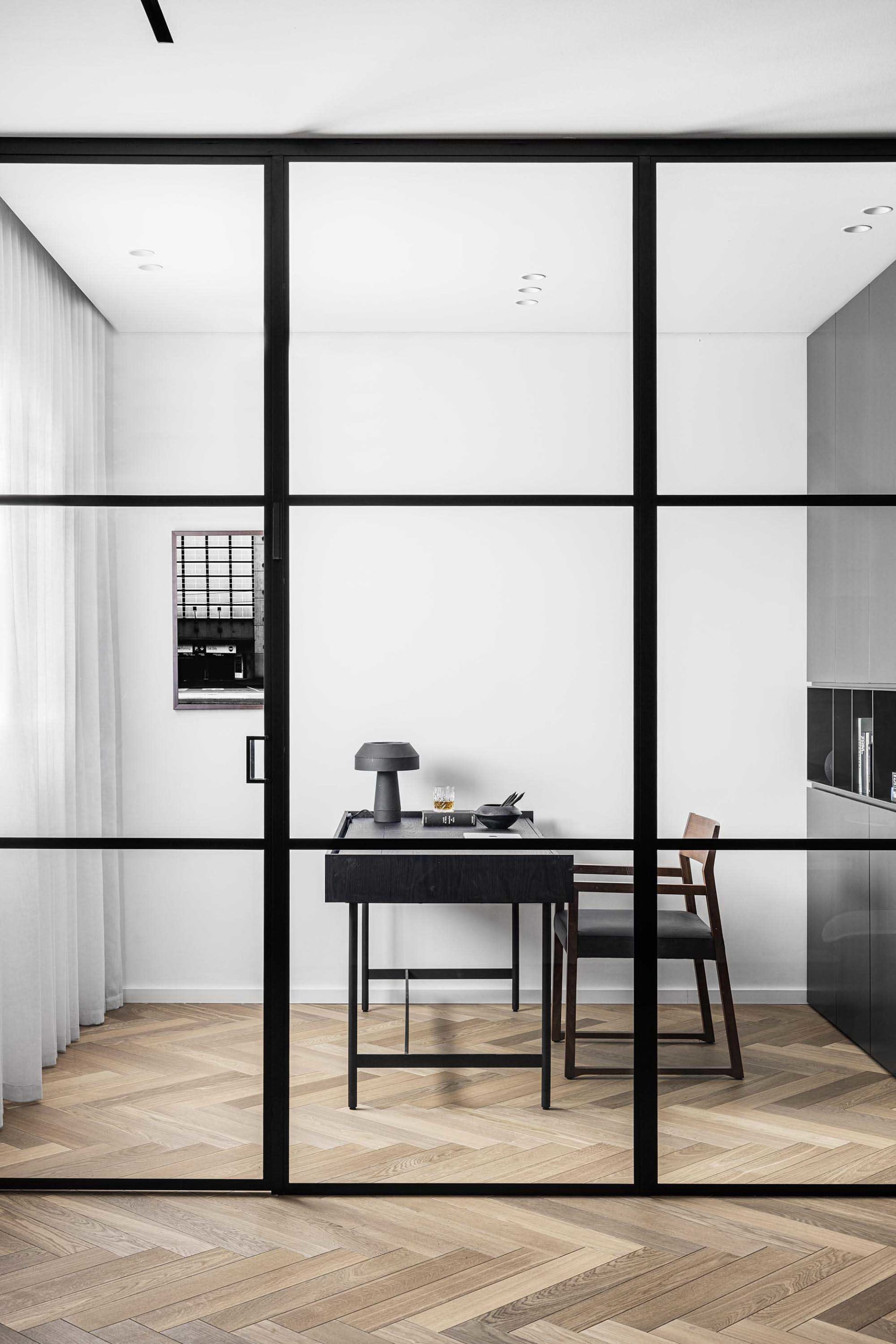 A sleek office space featuring a minimalist design with glass walls and wooden flooring.