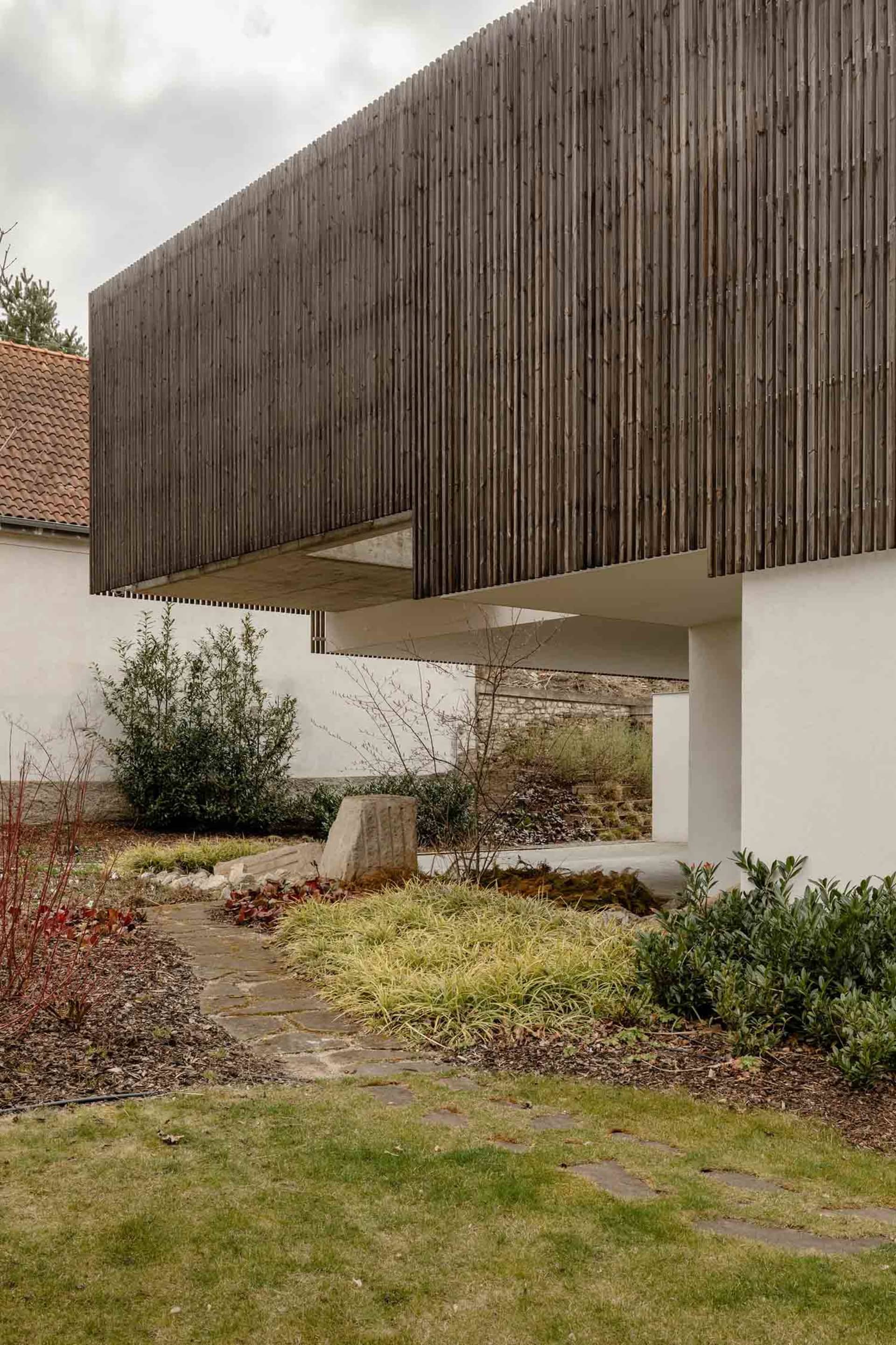 The minimalist exterior of a modern house features a wooden paneled wall.
