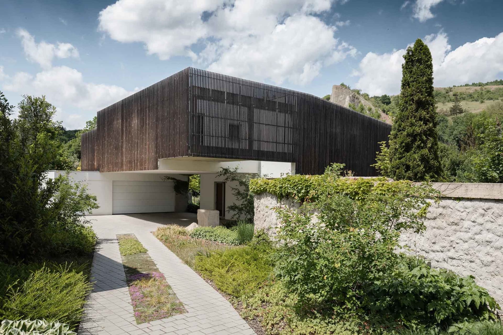 Modern residential home with wooden exterior and greenery surrounding.
