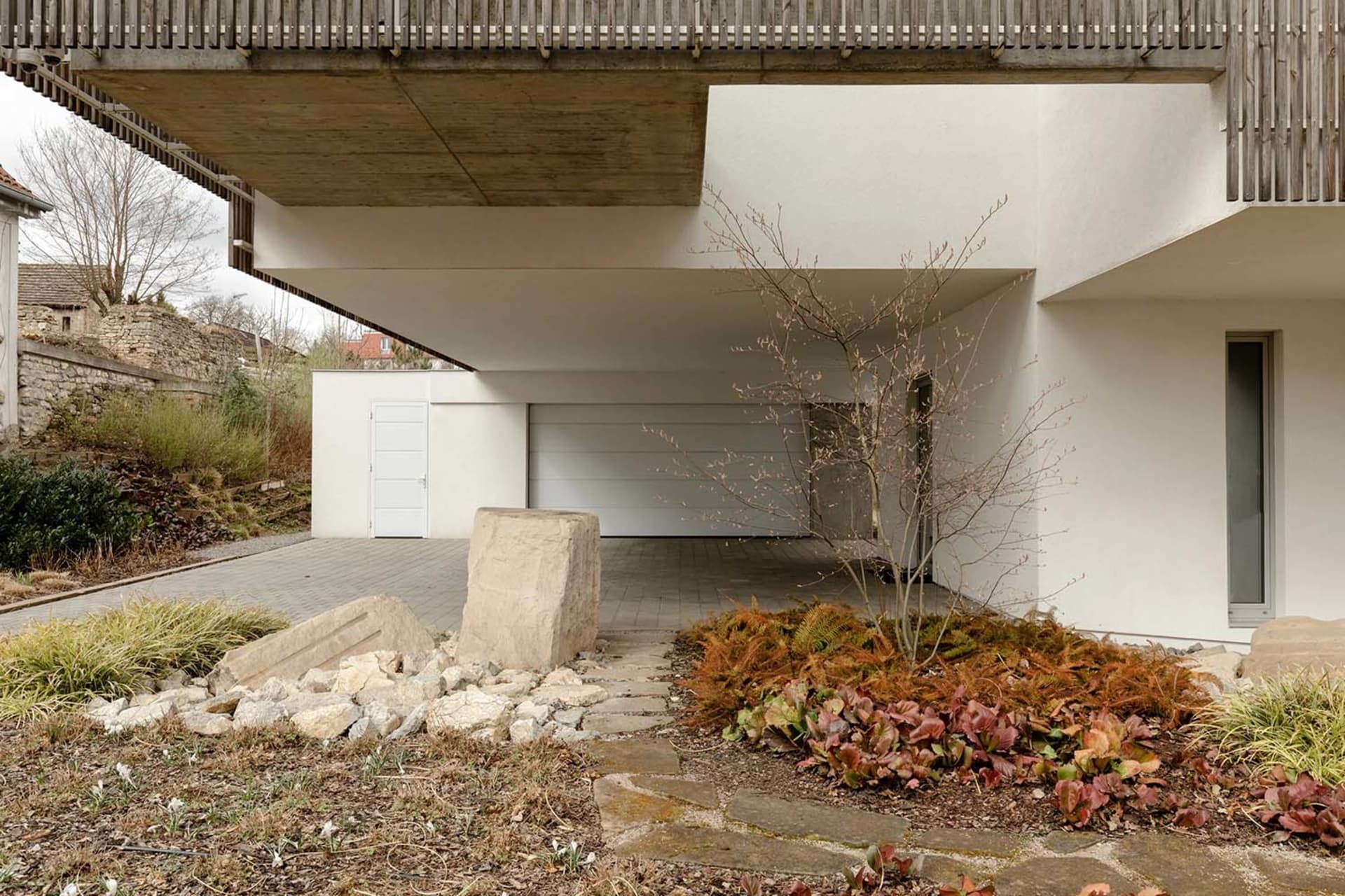 一棟現代住宅,設有混凝土車道、石板步道與花園。