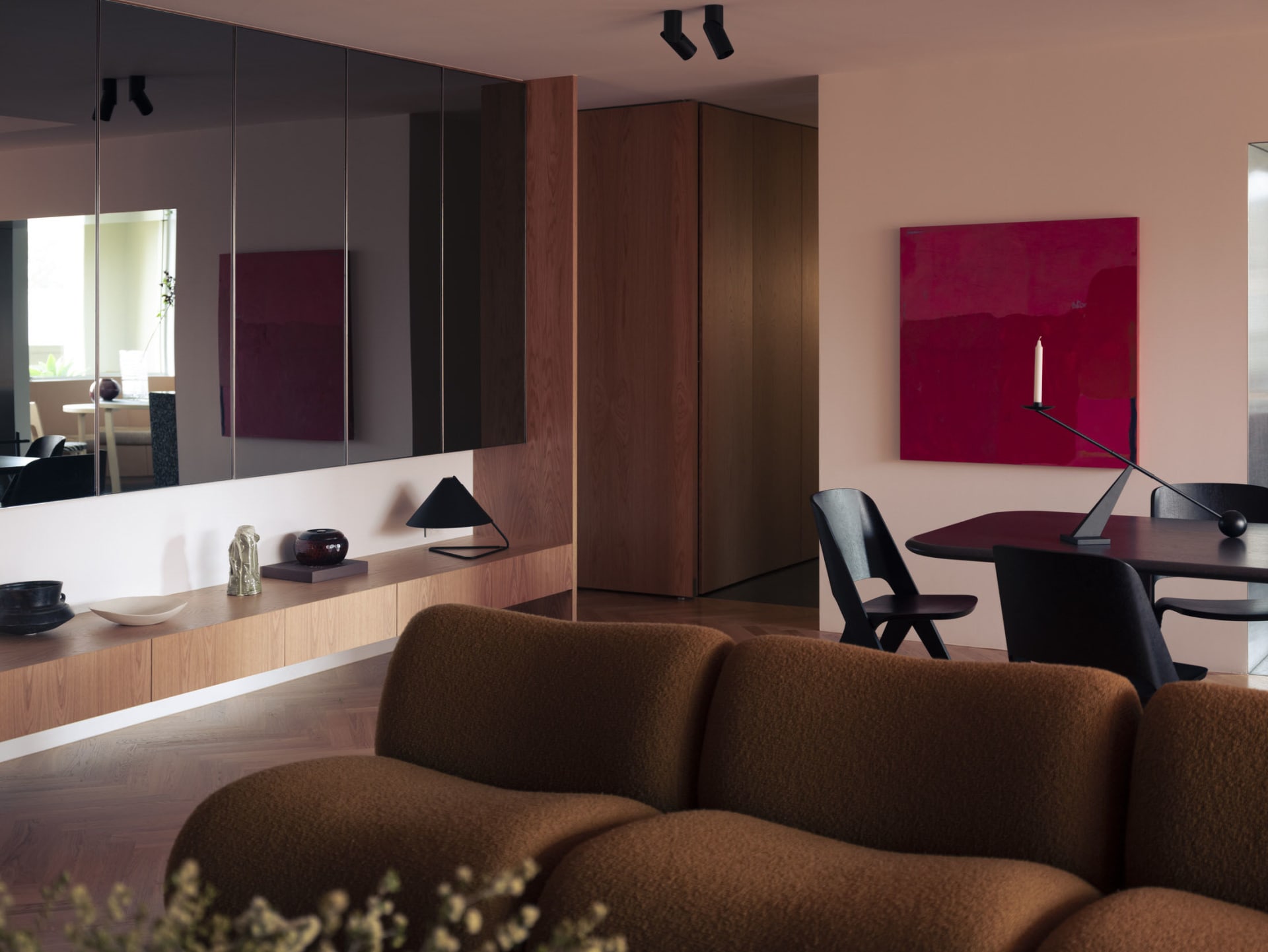 Modern living room with plush brown couch, wooden cabinets, and a red abstract painting on the wall.