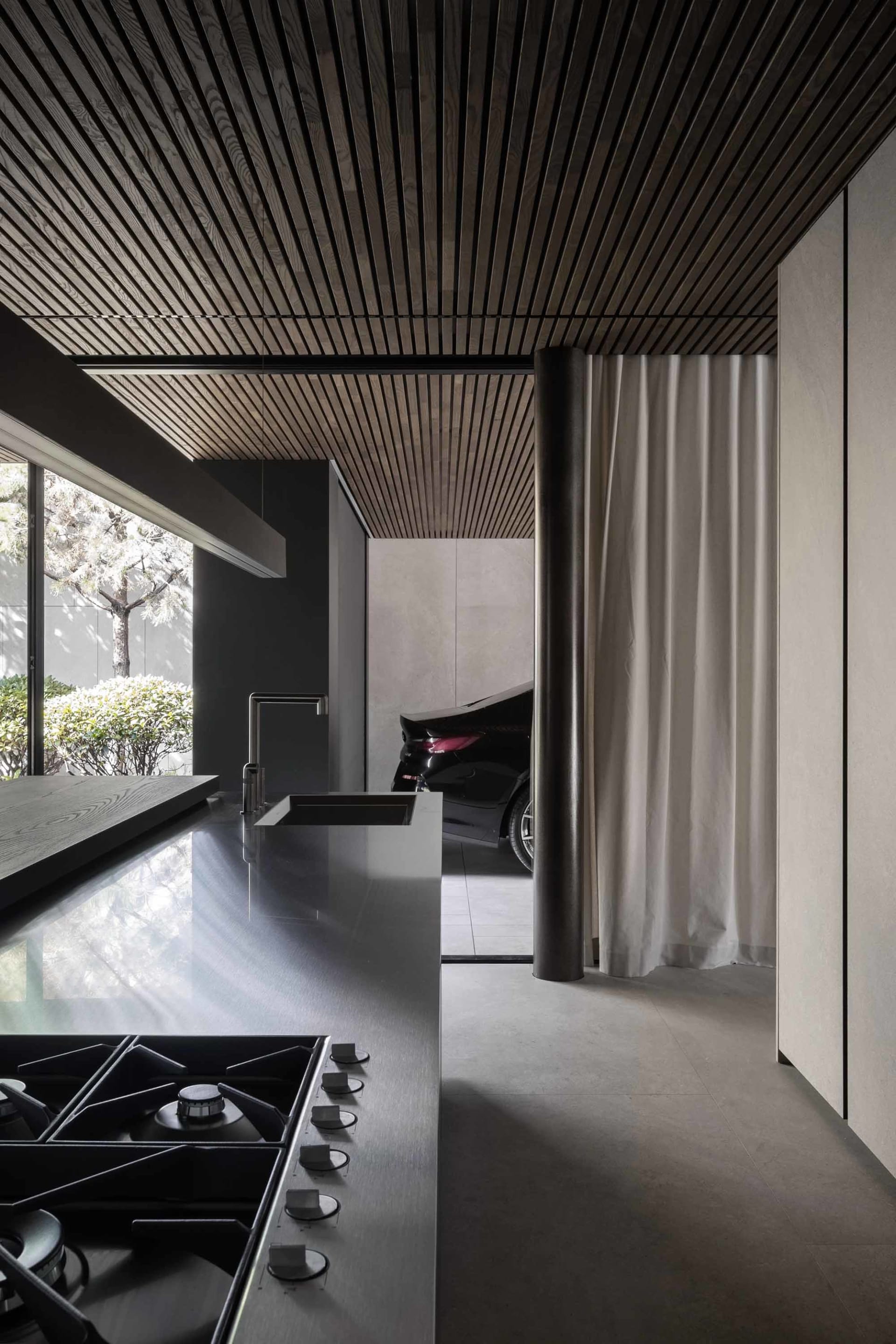 A modern minimalist kitchen with a wood-paneled ceiling and concrete countertops.