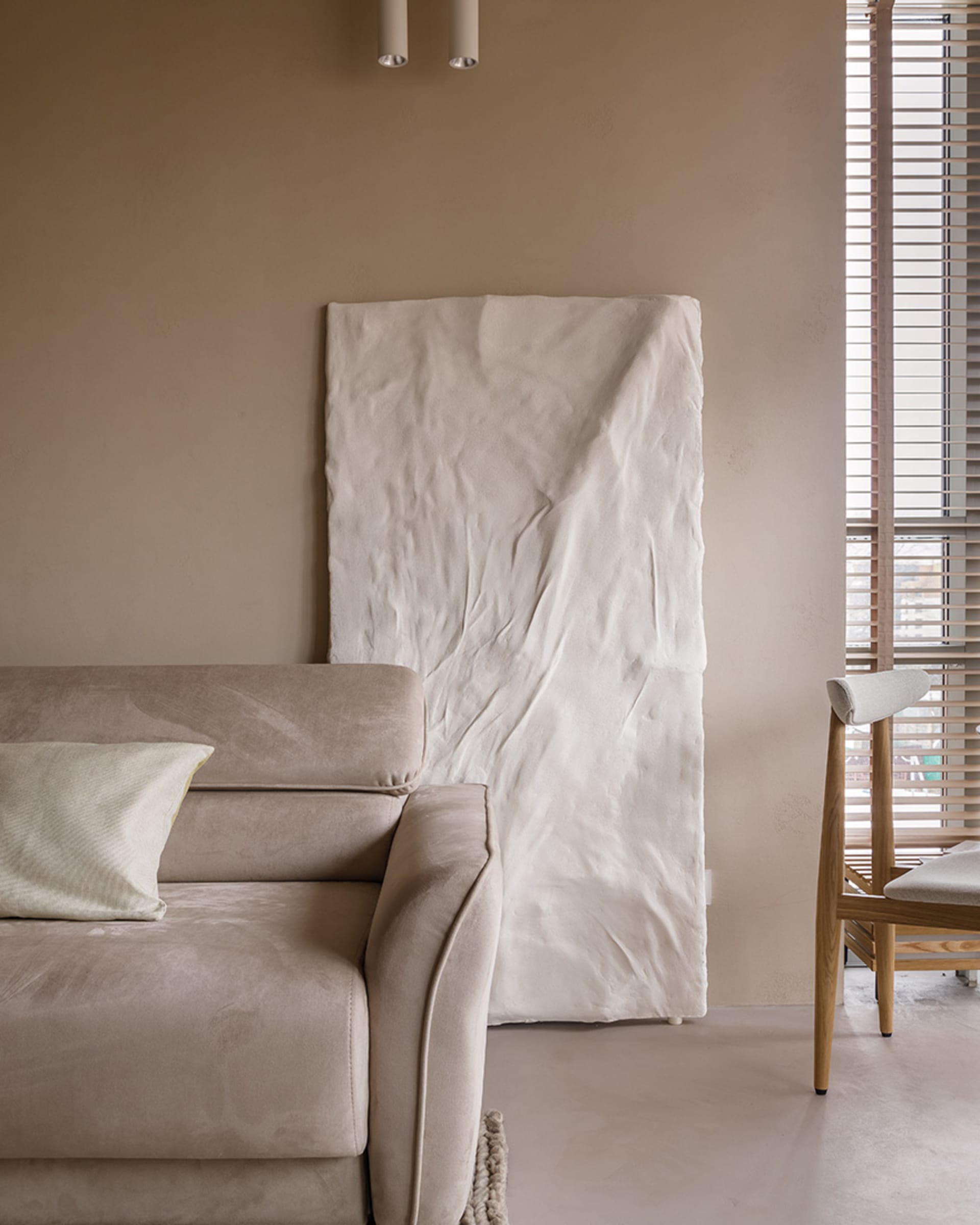 Minimalist living room featuring a white canvas and a beige couch with pillows.