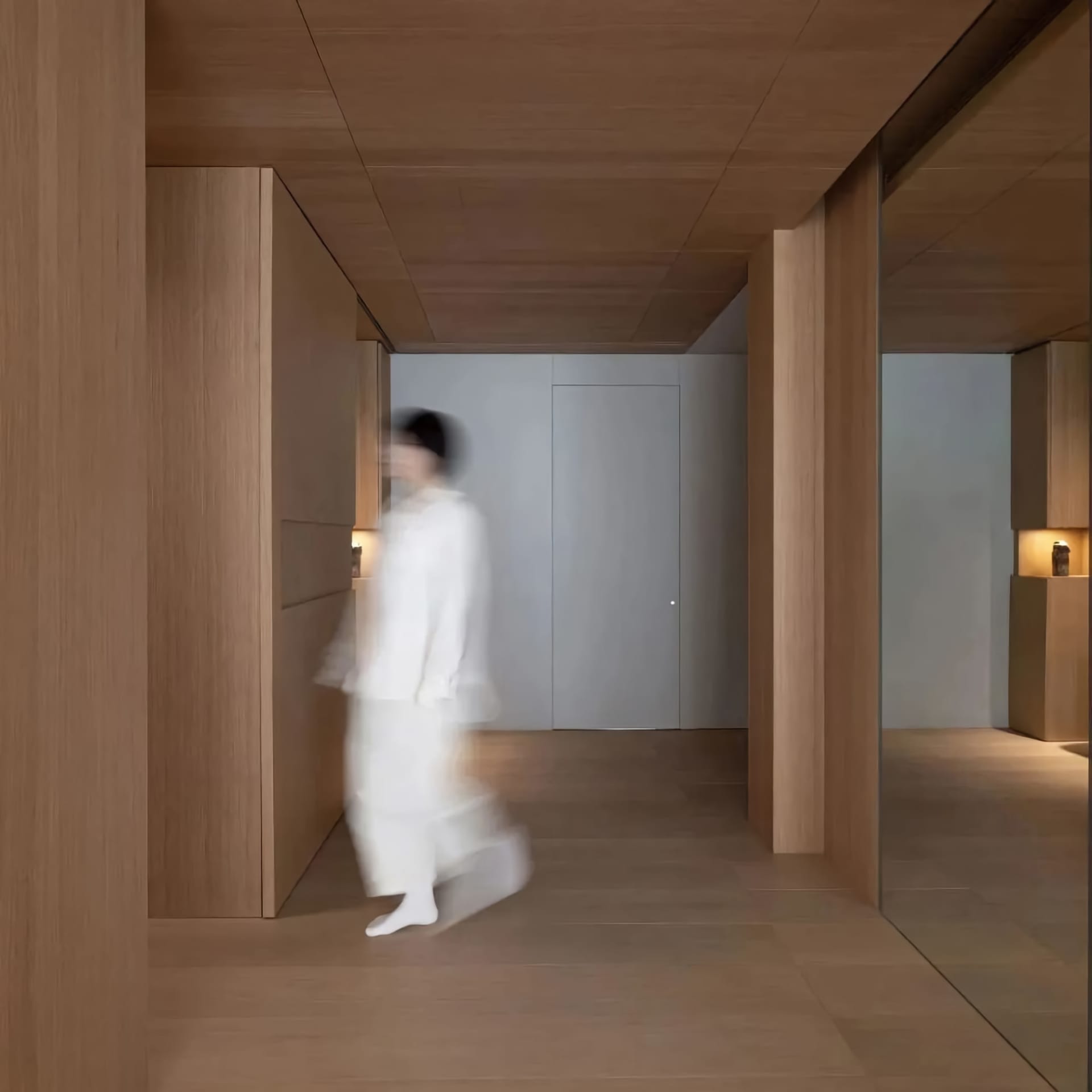 A modern interior space with wooden walls and doors, featuring a blurred figure walking through the corridor.