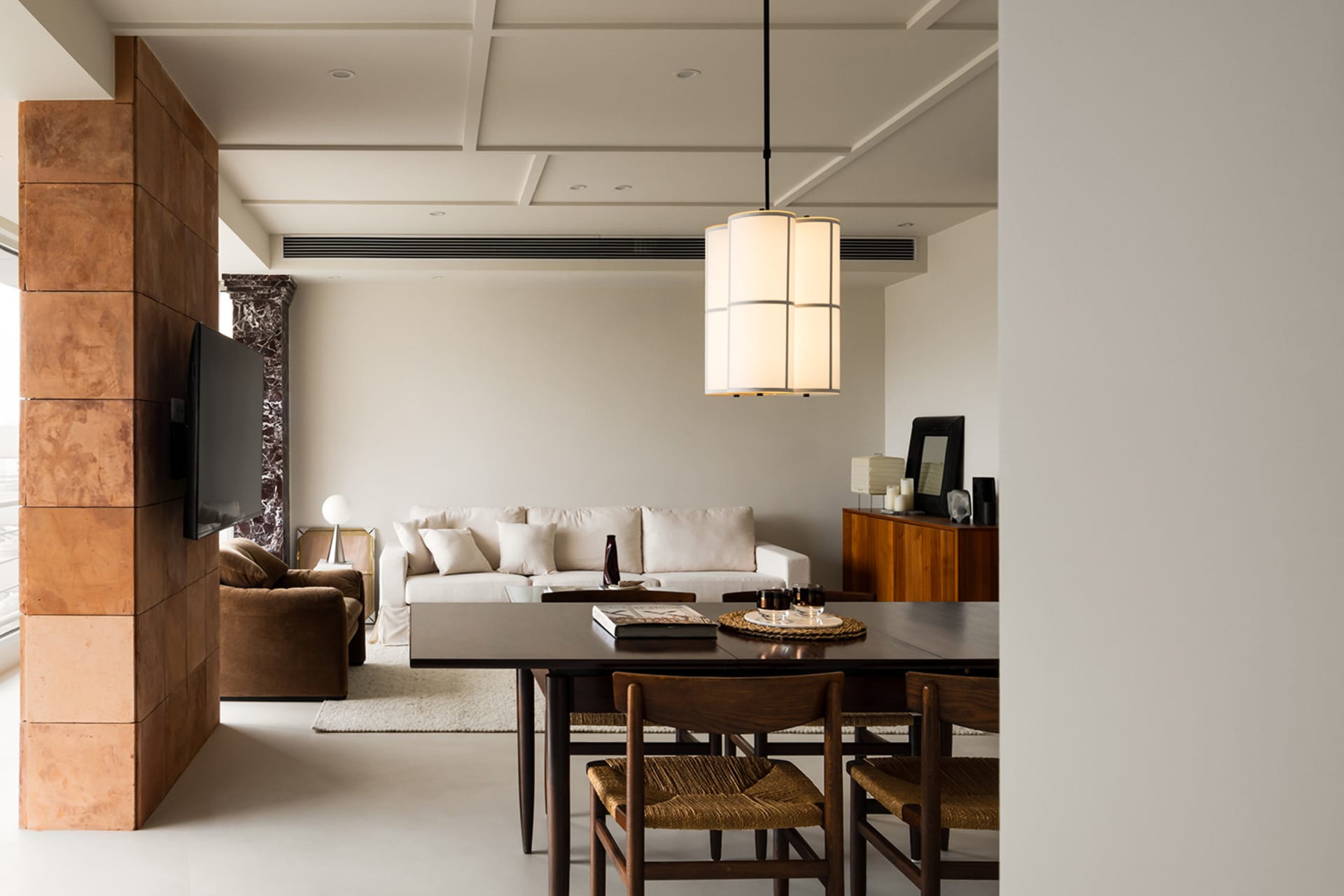 A modern minimalist living room featuring wooden furniture, white walls, and a white sofa with white cushions.
