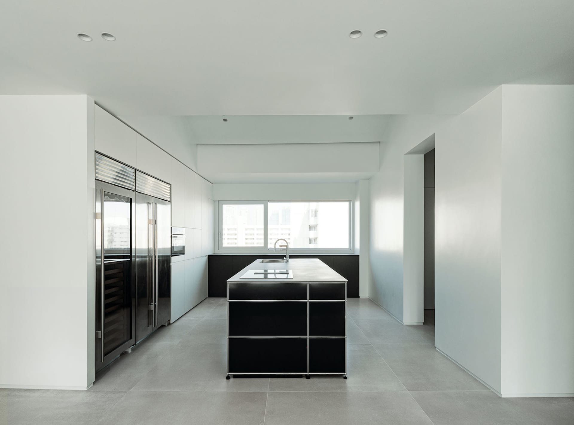 A modern kitchen with black metal cabinets and a concrete floor.