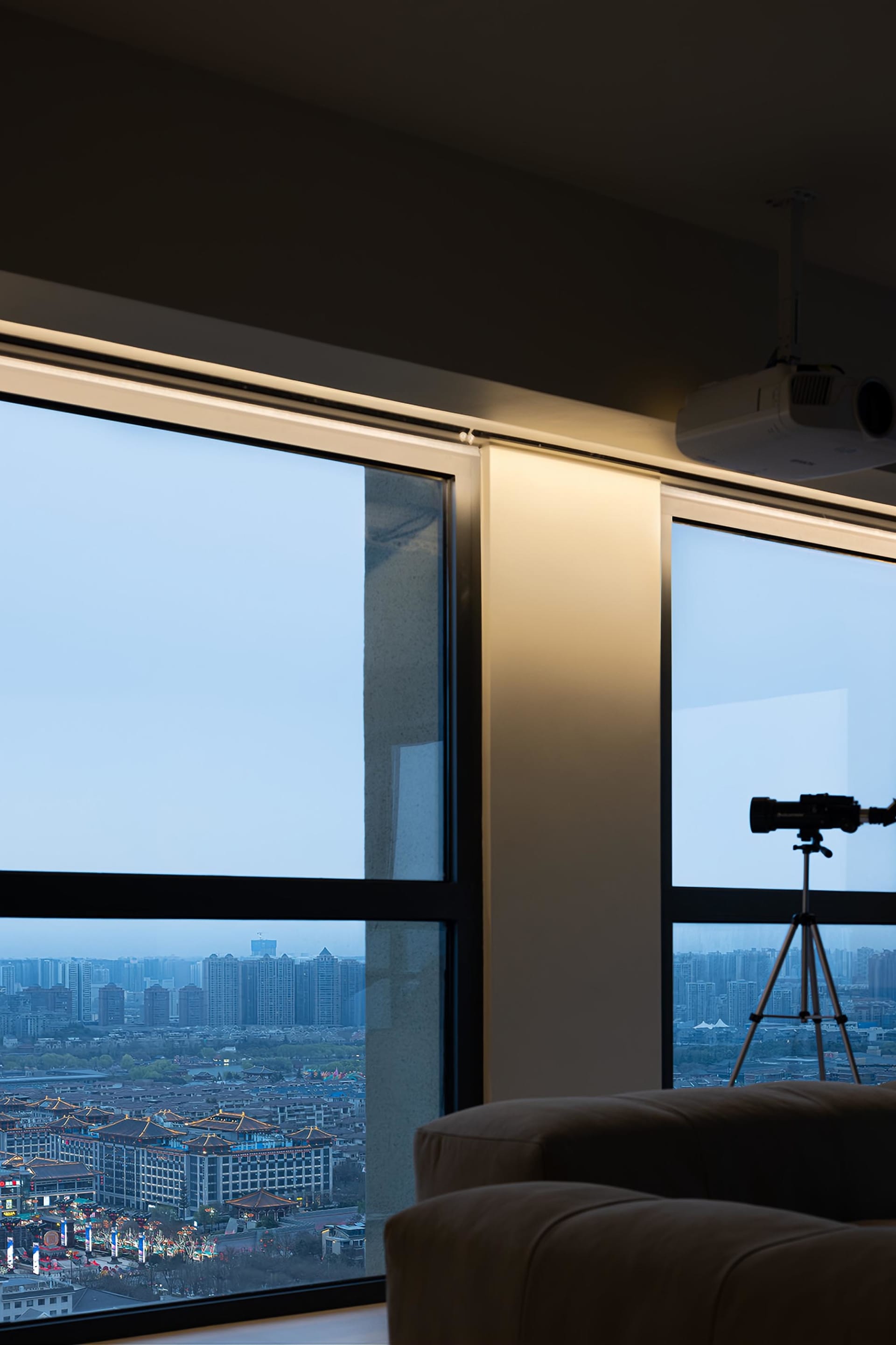 Modern living room with glass windows overlooking a cityscape.