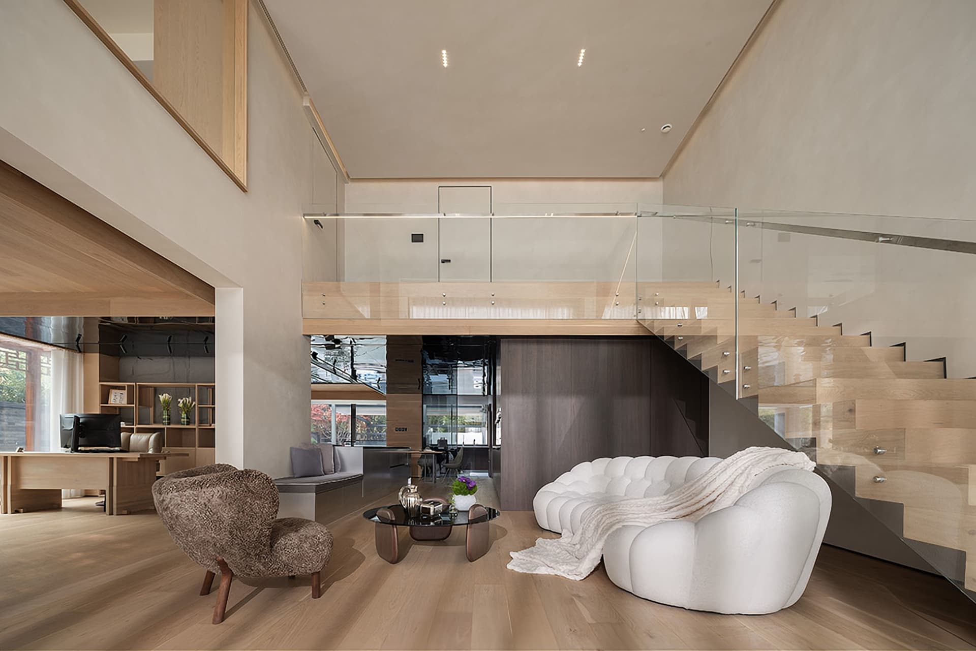 Modern living room with white sofa, wood furniture, and glass railing on the second floor.