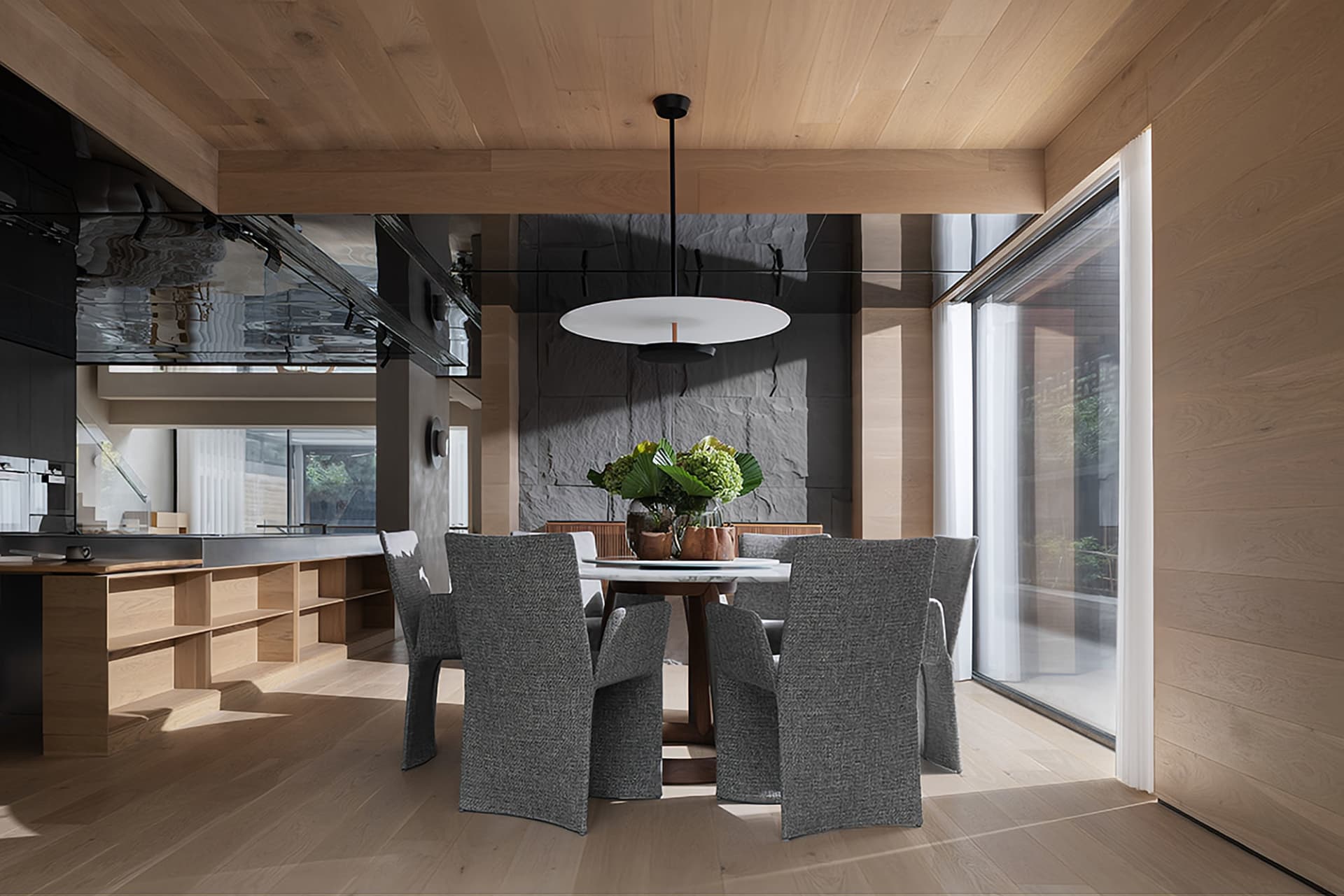 Modern dining room featuring wooden elements and a round table with chairs and a centerpiece plant.
