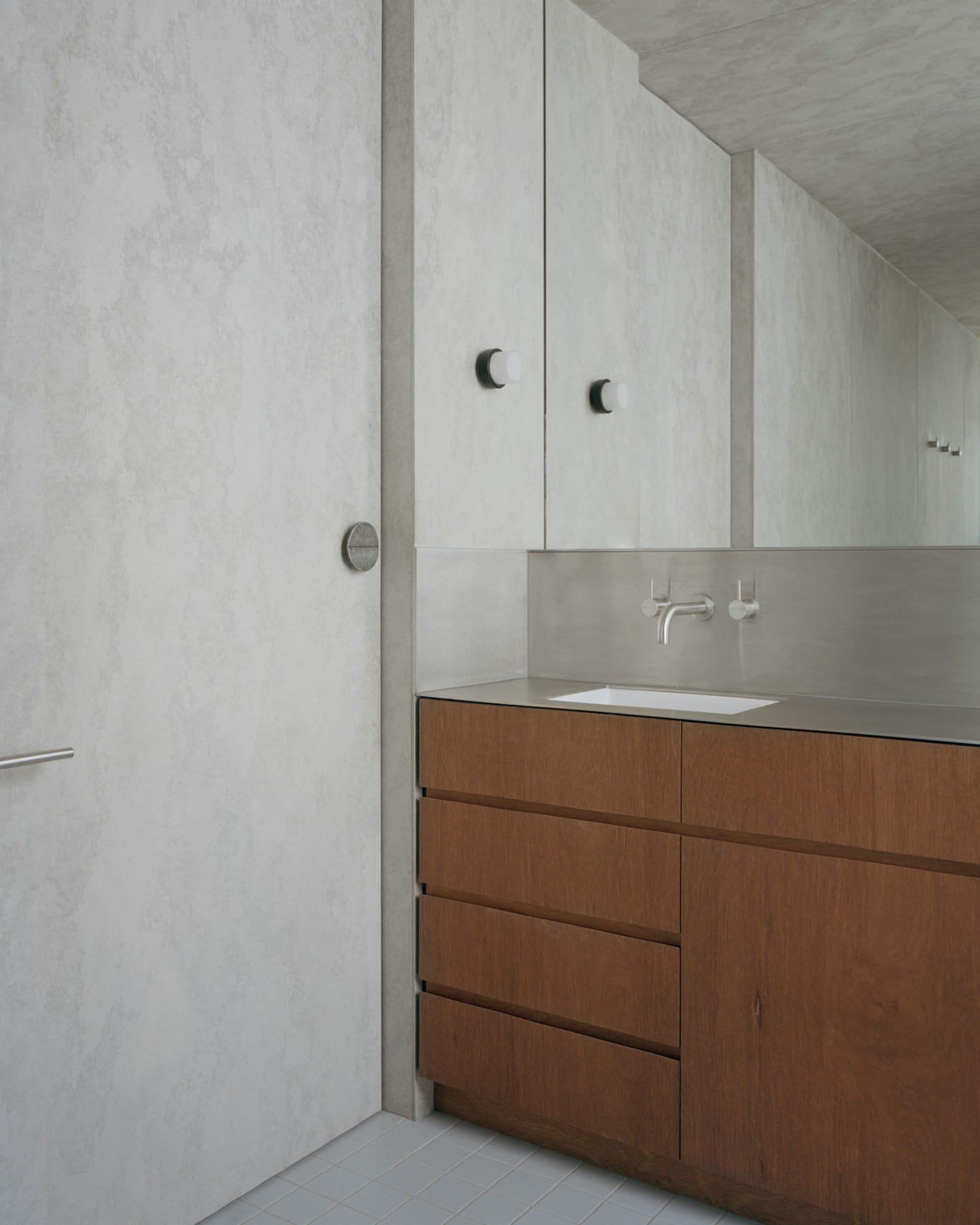 A minimalist bathroom with concrete walls and wooden vanity.